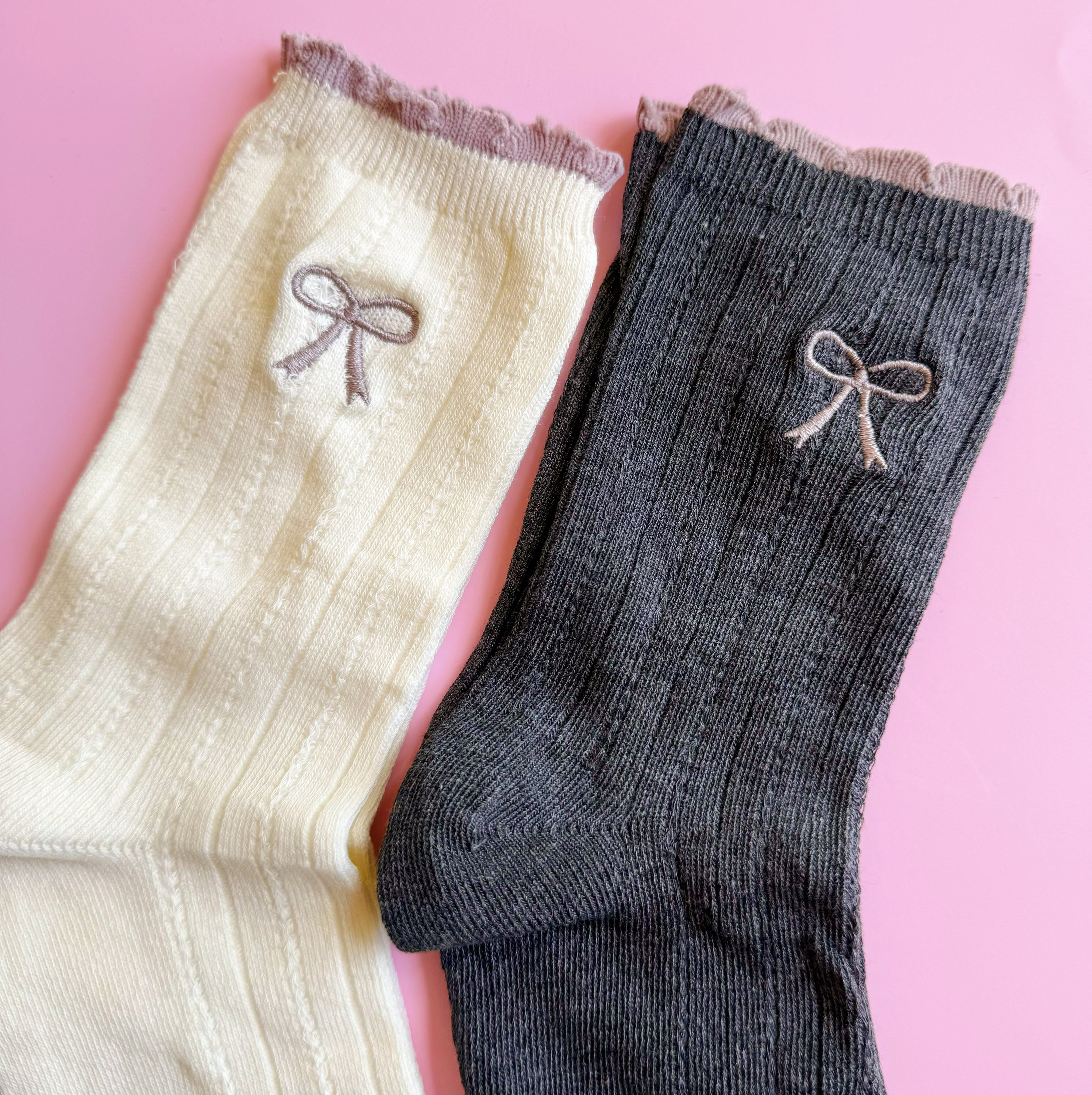 A set of two cute socks featuring embroidered bows, showcasing their soft fabric and stylish design.