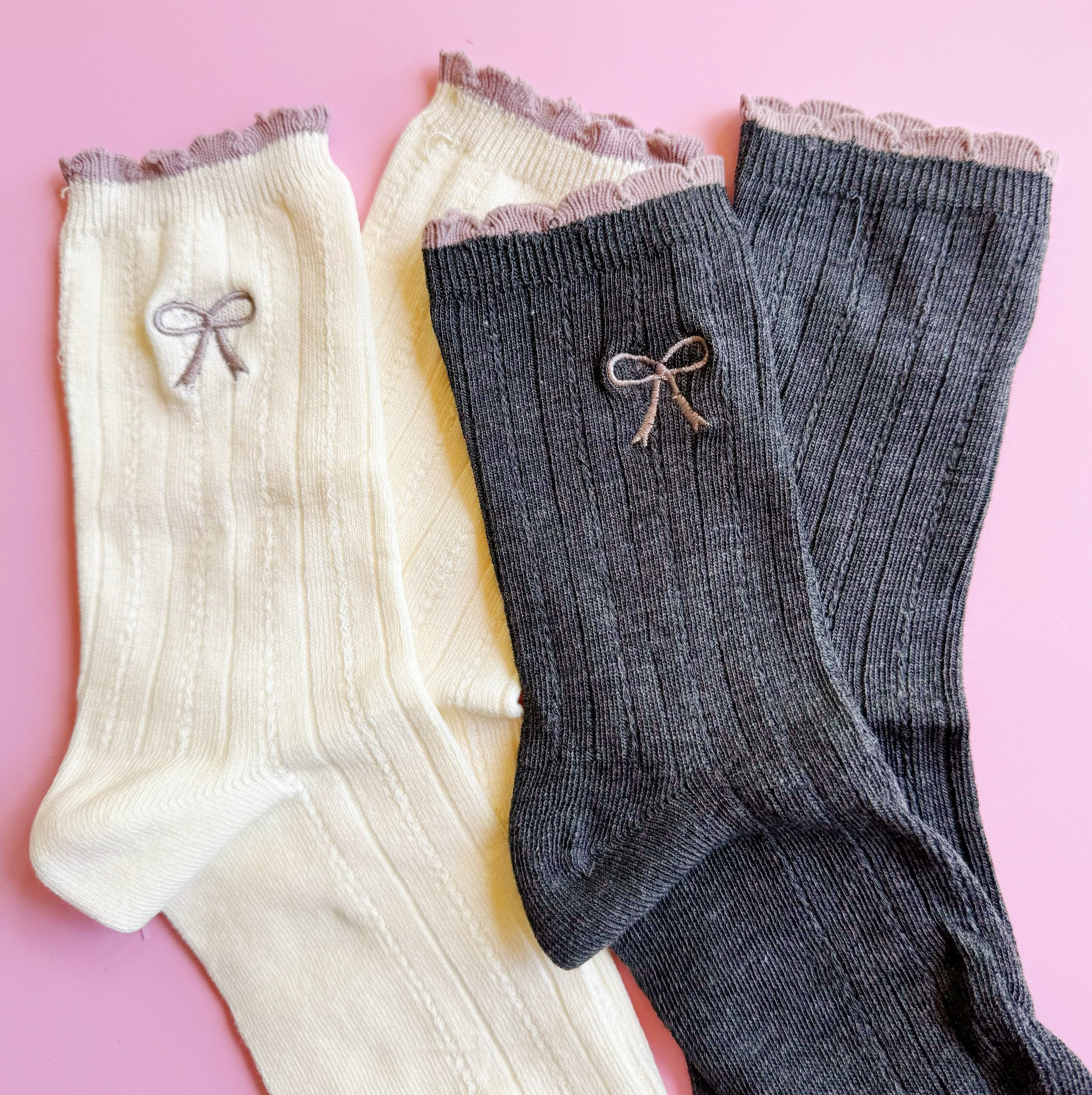 A set of two cute socks featuring embroidered bows, showcasing their soft fabric and stylish design.