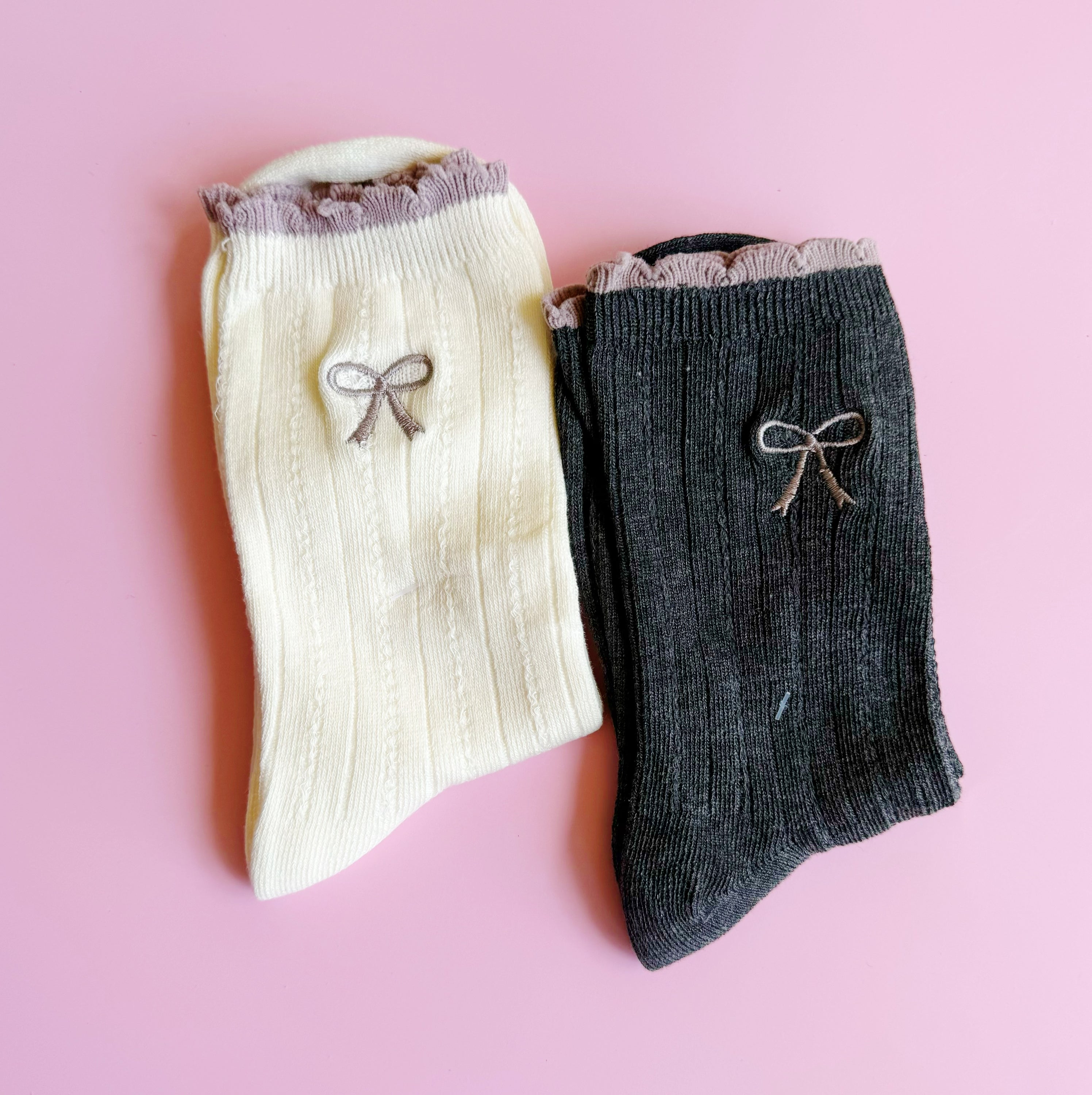 A set of two cute socks featuring embroidered bows, showcasing their soft fabric and stylish design.