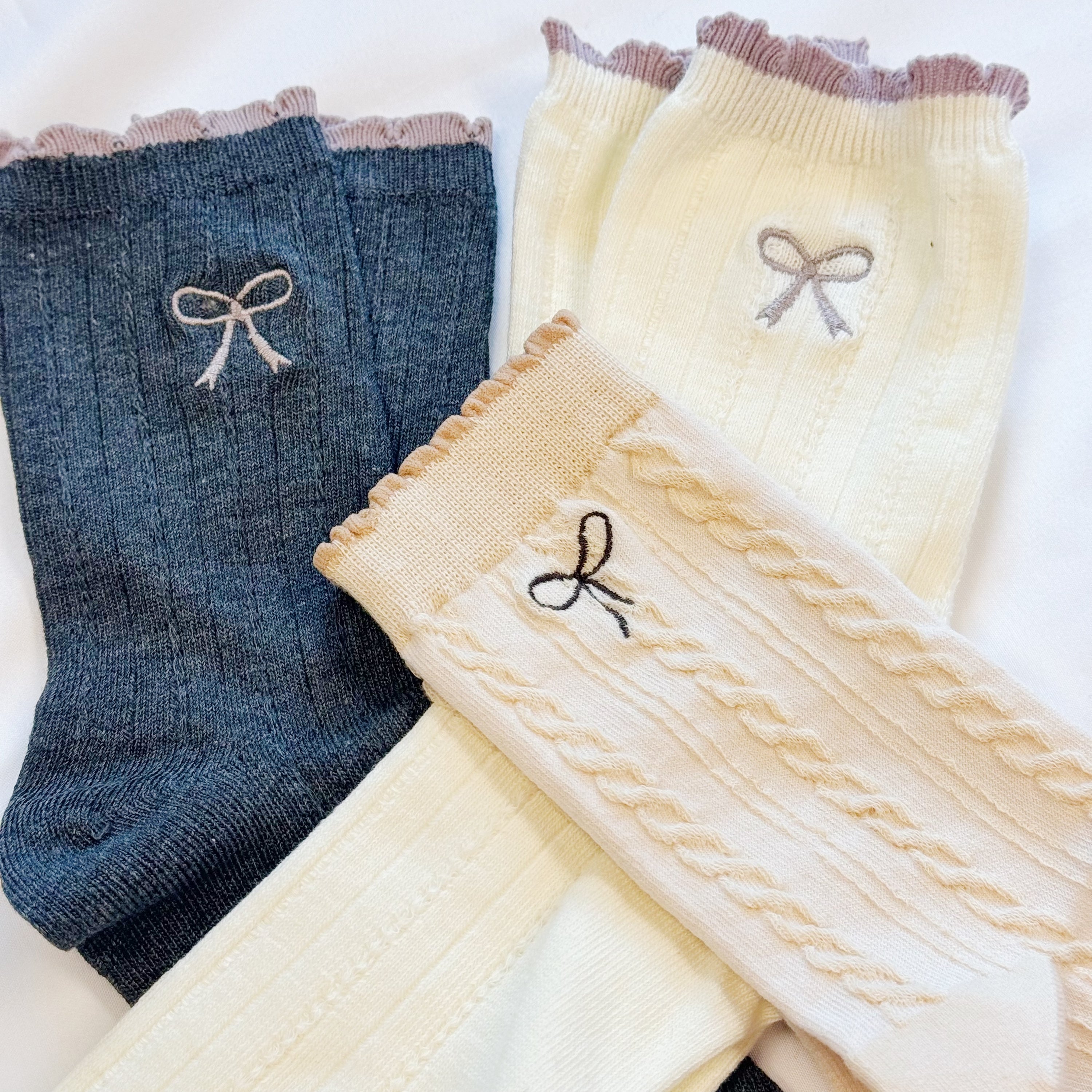 A set of two cute socks featuring embroidered bows, showcasing their soft fabric and stylish design.