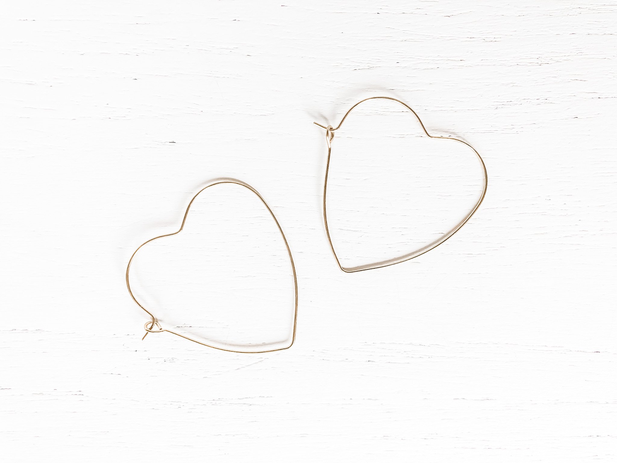 A pair of elegant brass heart hoop earrings, measuring 1 5/8 inches long, showcasing a stylish design perfect for any occasion.