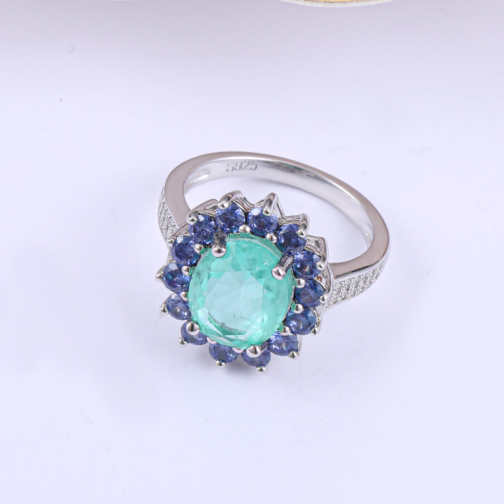 A beautiful Brazilian created blue tourmaline Paraiba halo ring set in 925 sterling silver with a white gold finish, showcasing a vibrant blue stone.