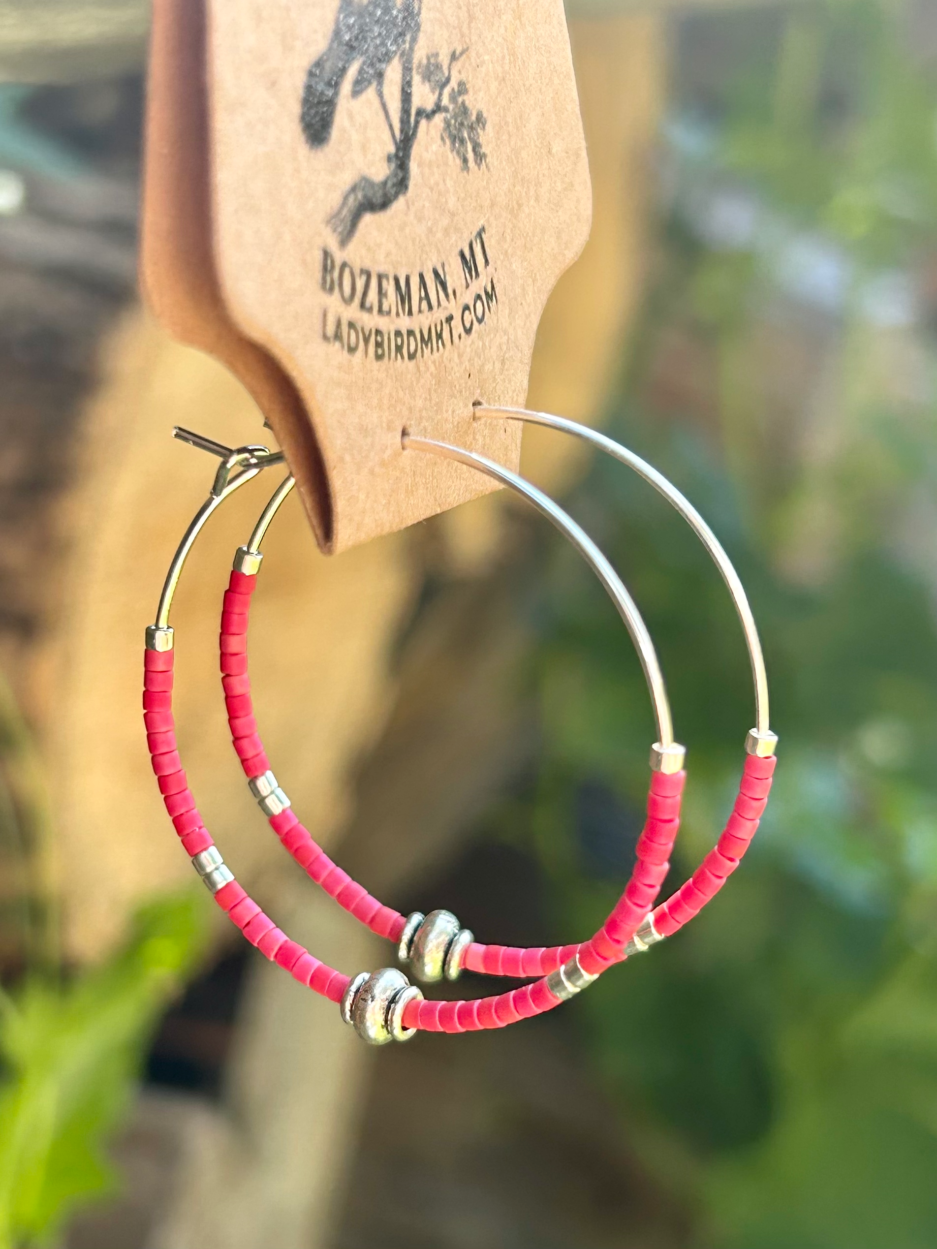 A pair of vibrant brick red and silver beaded hoop earrings featuring Miyuki Delica seed beads on a stainless steel hoop.