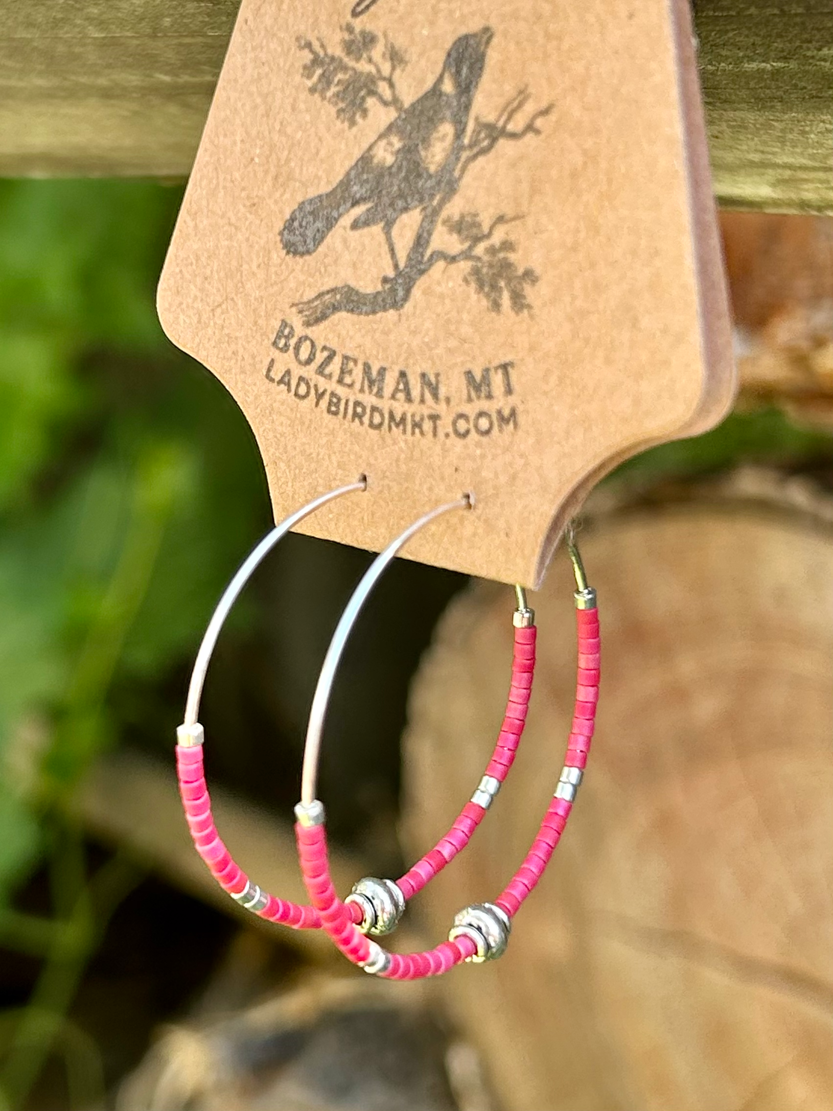 A pair of vibrant brick red and silver beaded hoop earrings featuring Miyuki Delica seed beads on a stainless steel hoop.