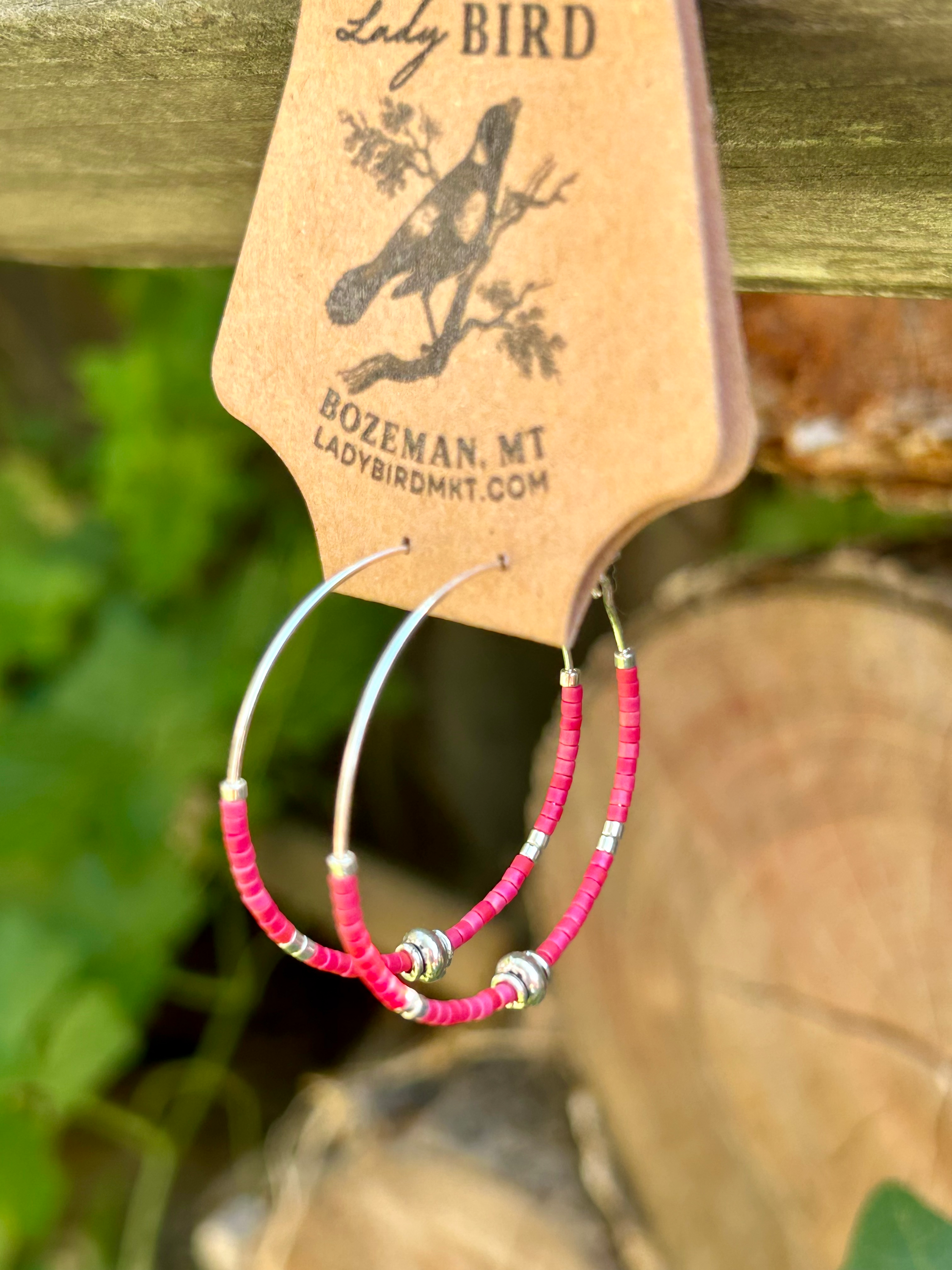 A pair of vibrant brick red and silver beaded hoop earrings featuring Miyuki Delica seed beads on a stainless steel hoop.