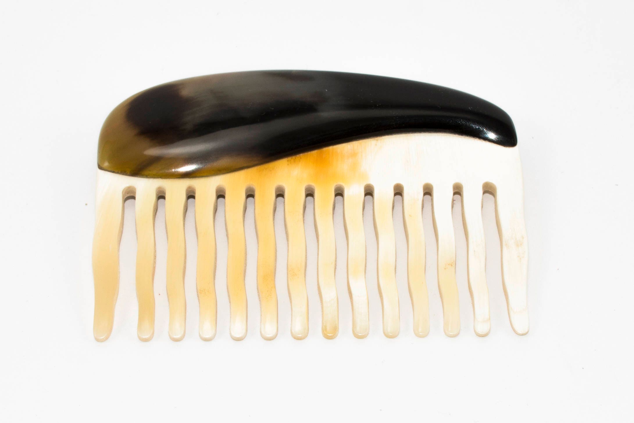 A beautifully crafted Buffalo Horn Comb with rounded teeth, showcasing its unique natural patterns and polished finish.