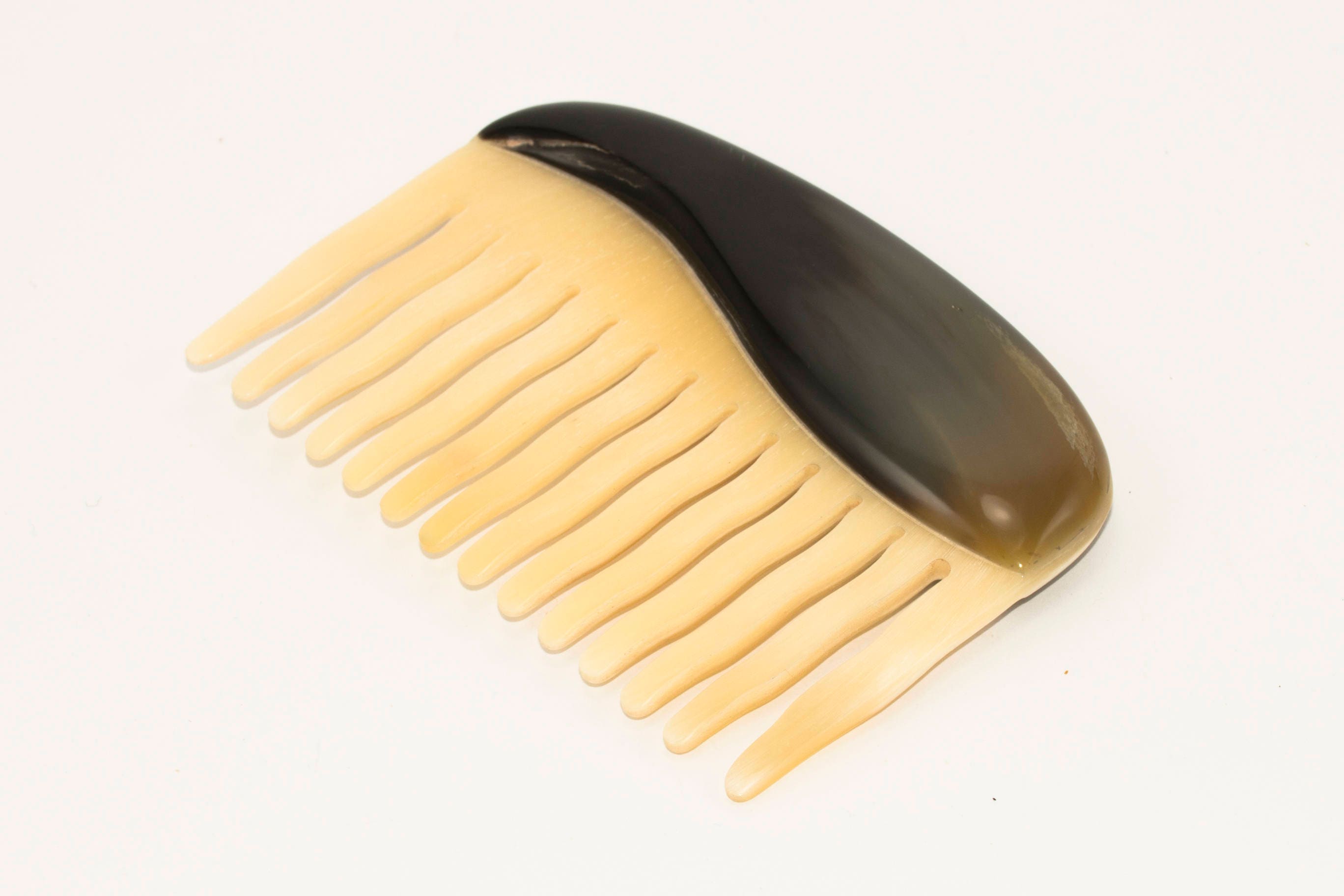 A beautifully crafted Buffalo Horn Comb with rounded teeth, showcasing its unique natural patterns and polished finish.