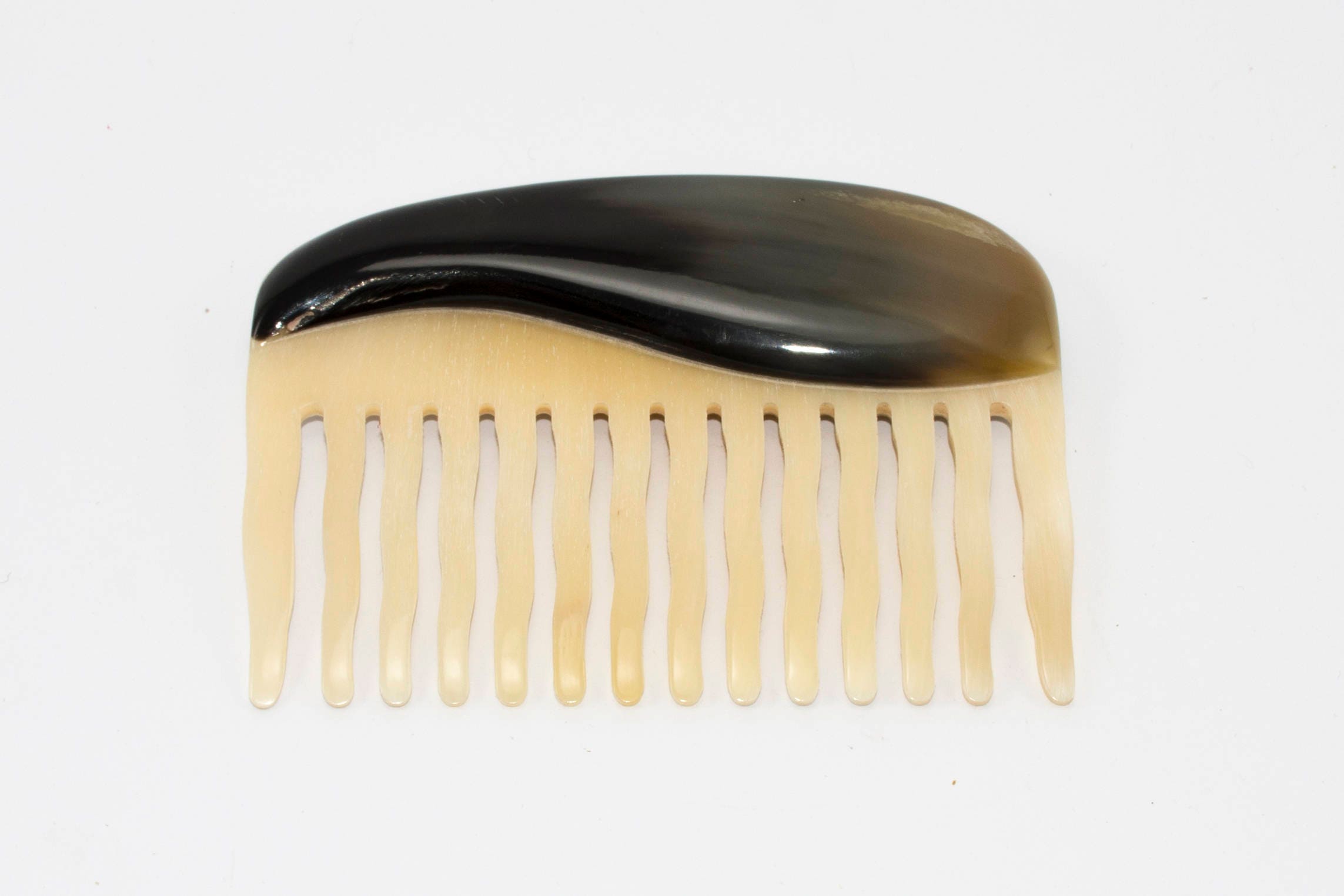 A beautifully crafted Buffalo Horn Comb with rounded teeth, showcasing its unique natural patterns and polished finish.