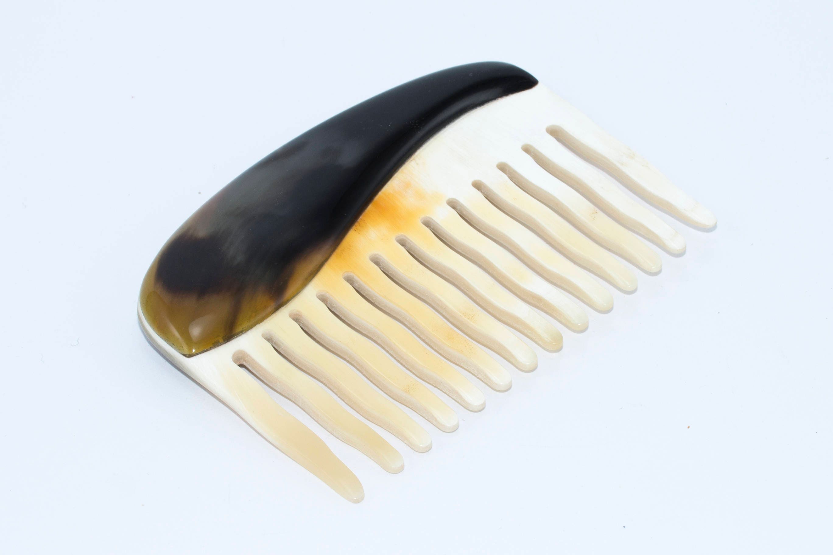 A beautifully crafted Buffalo Horn Comb with rounded teeth, showcasing its unique natural patterns and polished finish.