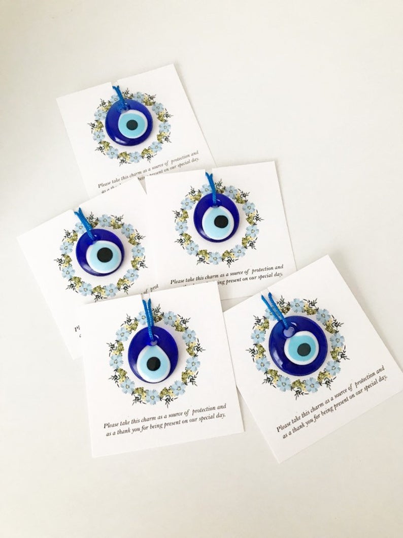 Bulk Greek wedding favors featuring handmade blue glass evil eye beads with personalized cards, symbolizing good luck and protection.