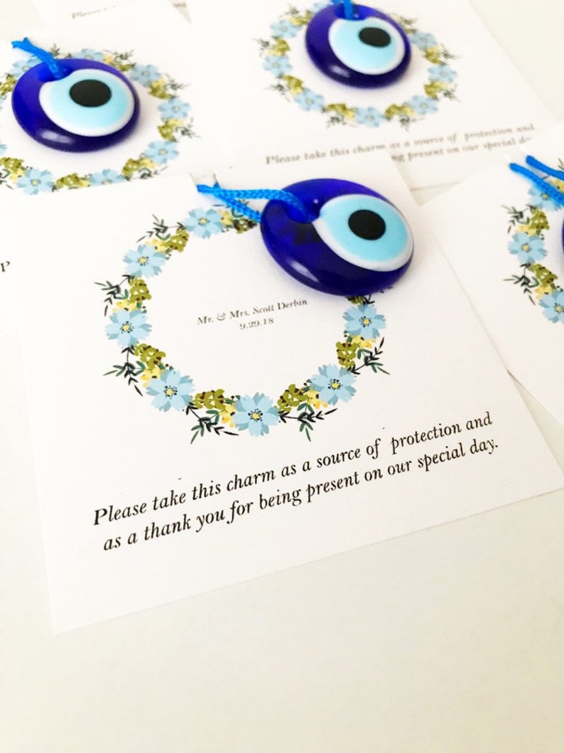 Bulk Greek wedding favors featuring handmade blue glass evil eye beads with personalized cards, symbolizing good luck and protection.