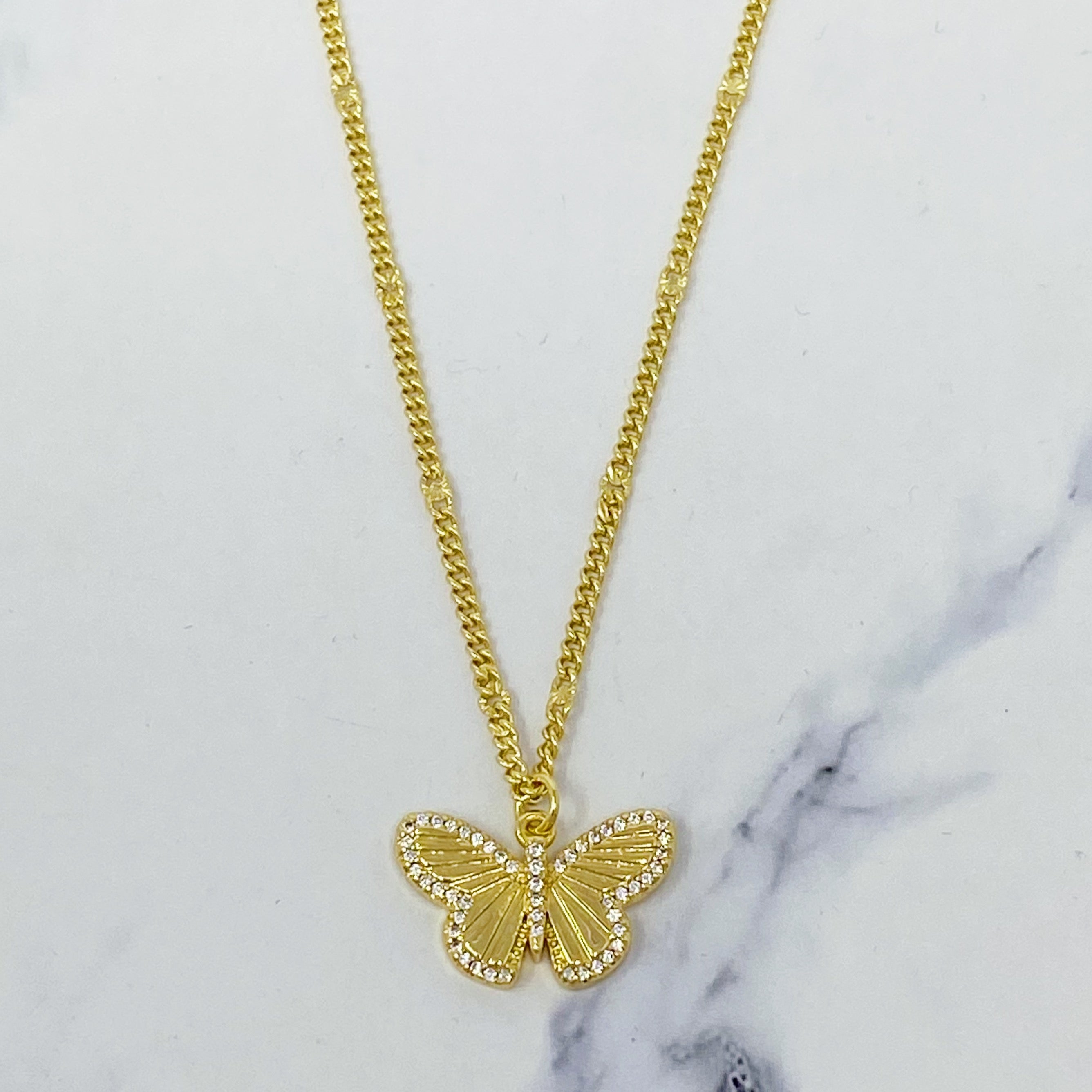 A delicate Butterfly In Flight Necklace featuring a detailed butterfly charm embellished with cubic zirconia stones on a gold plated brass chain.