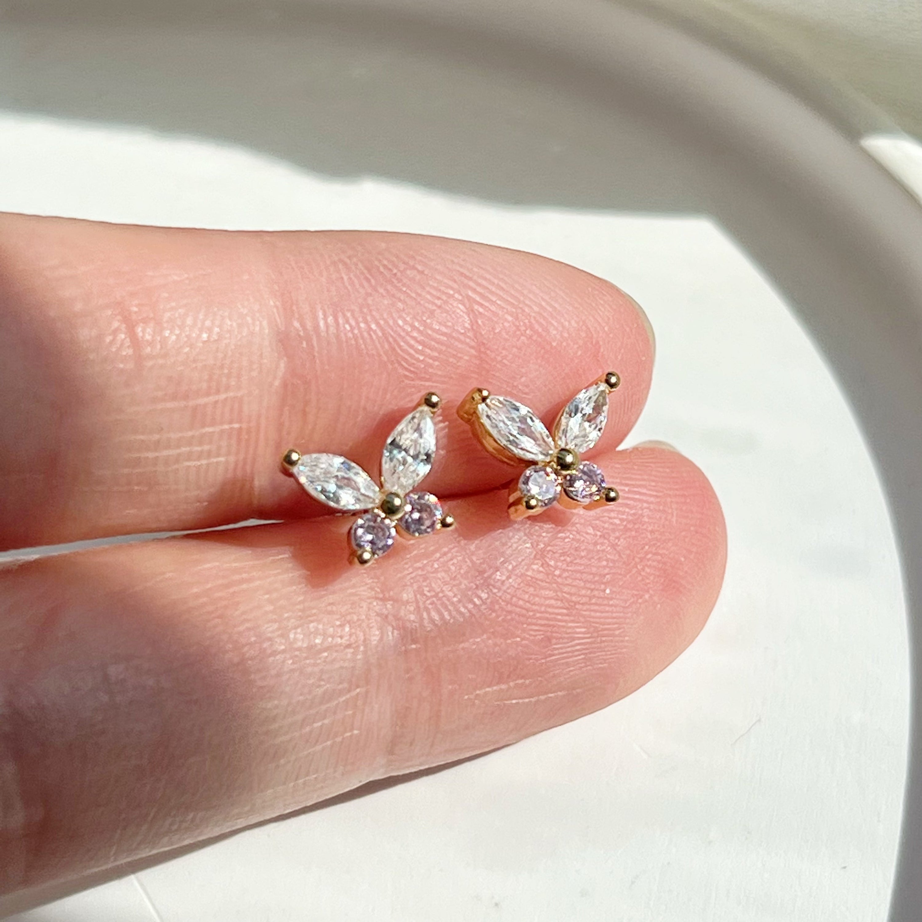 A pair of elegant butterfly gold stud earrings adorned with clear and pink zircon crystals, showcasing their delicate design.