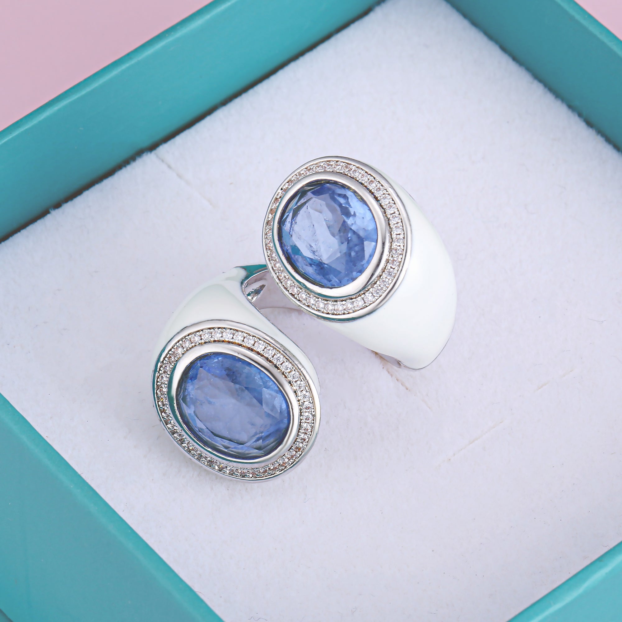 A stylish bypass silver ring featuring two large oval Palaiba aquamarine stones set in a modern design with white enamel.