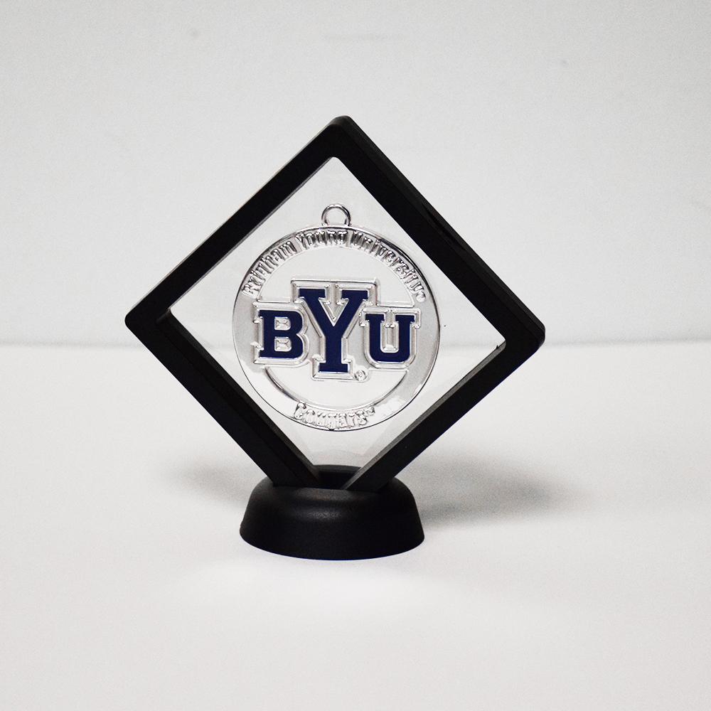 A silver BYU ornament displayed in a decorative black frame, showcasing its elegant design.