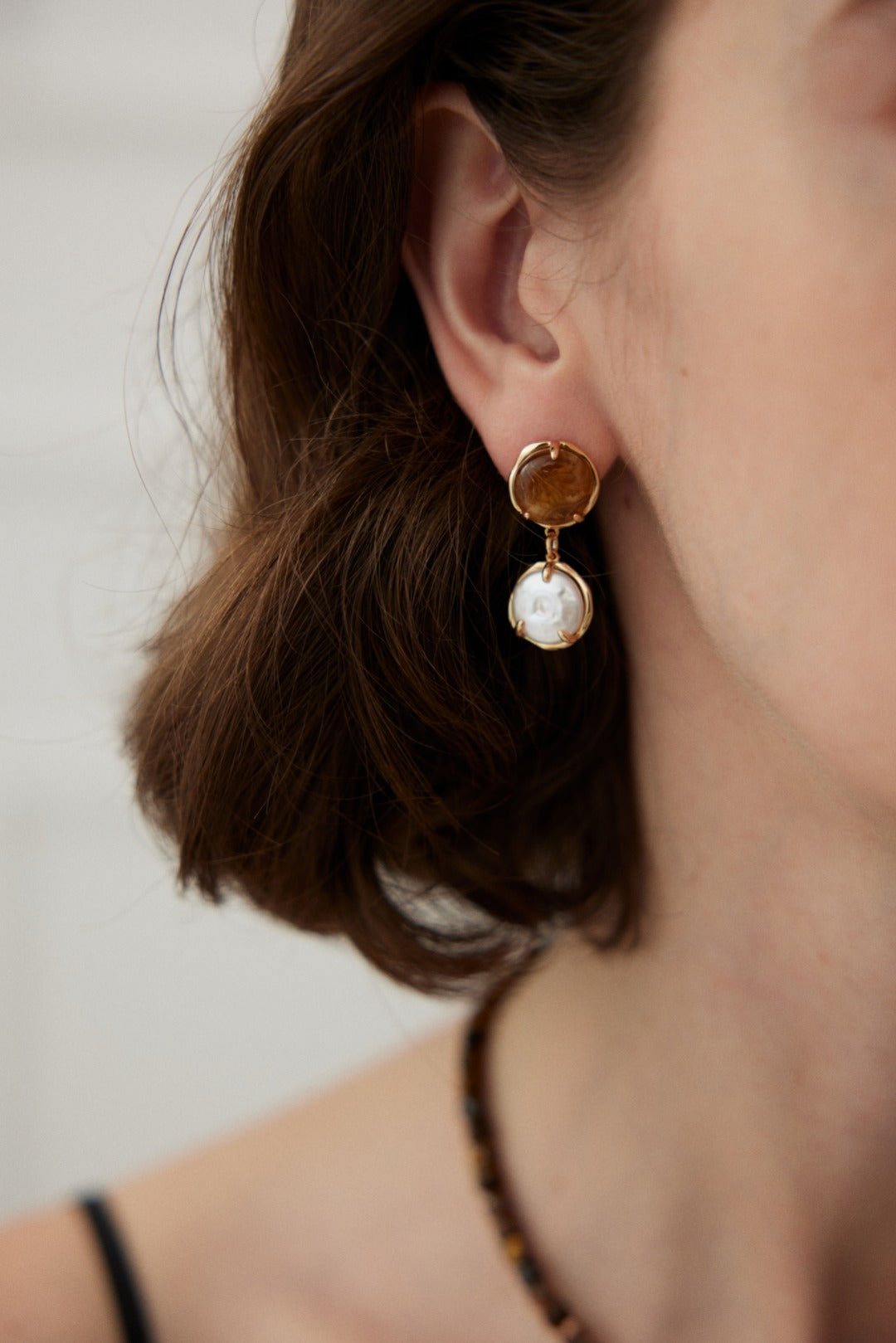 Café Au Lait Mini Pearl Ball Earring featuring vintage gold, coffee-colored resin, and delicate pearls, showcasing adjustable design for comfort.