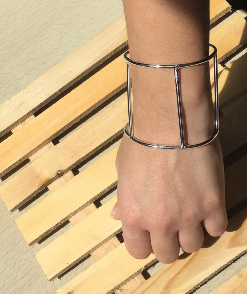 A stylish Cage Cuff Bracelet in gold and silver, showcasing its minimalist design and adjustable fit.