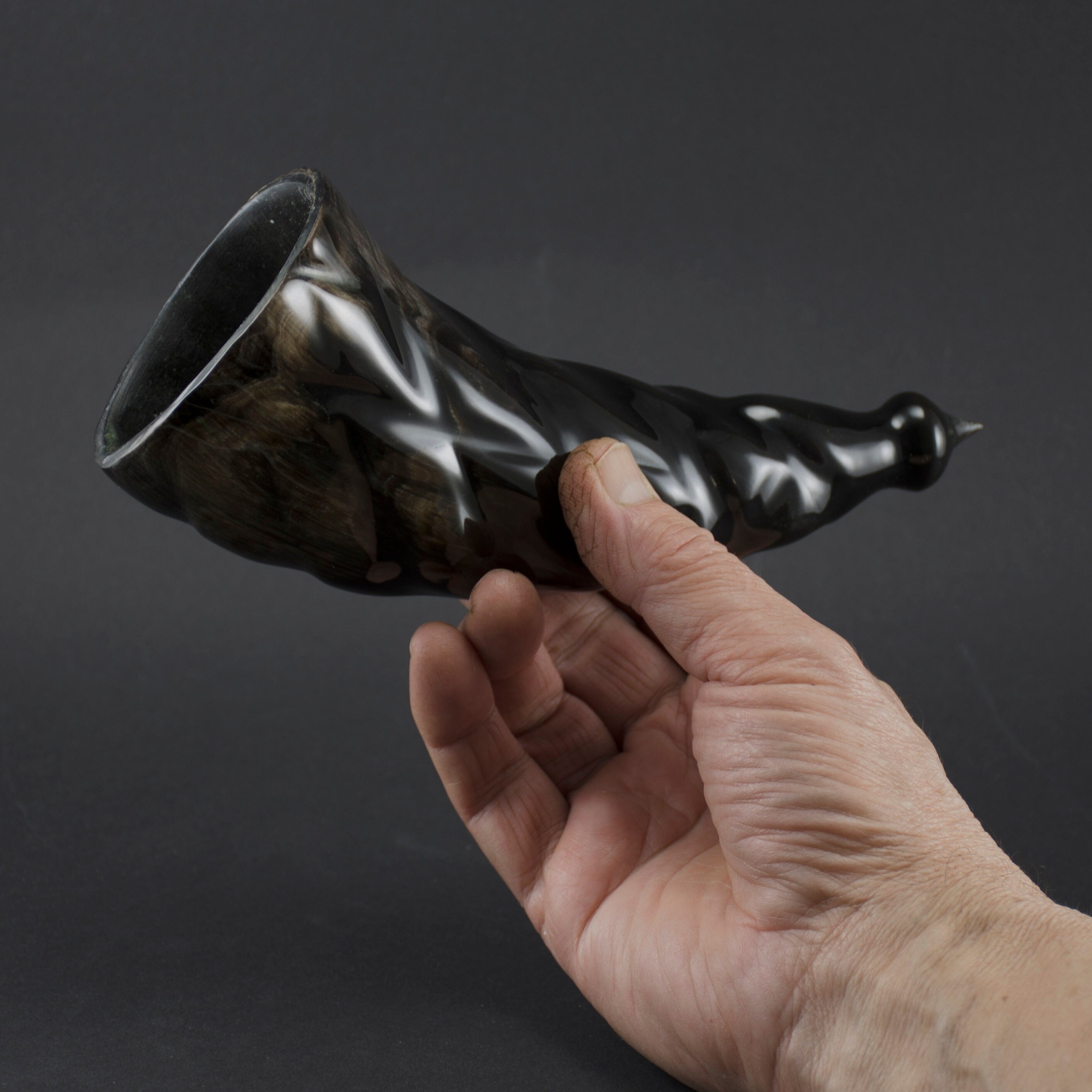 A beautifully carved drinking horn made from bull's horn, featuring intricate spiral ribbon designs and a polished finish, perfect for Viking-themed events.