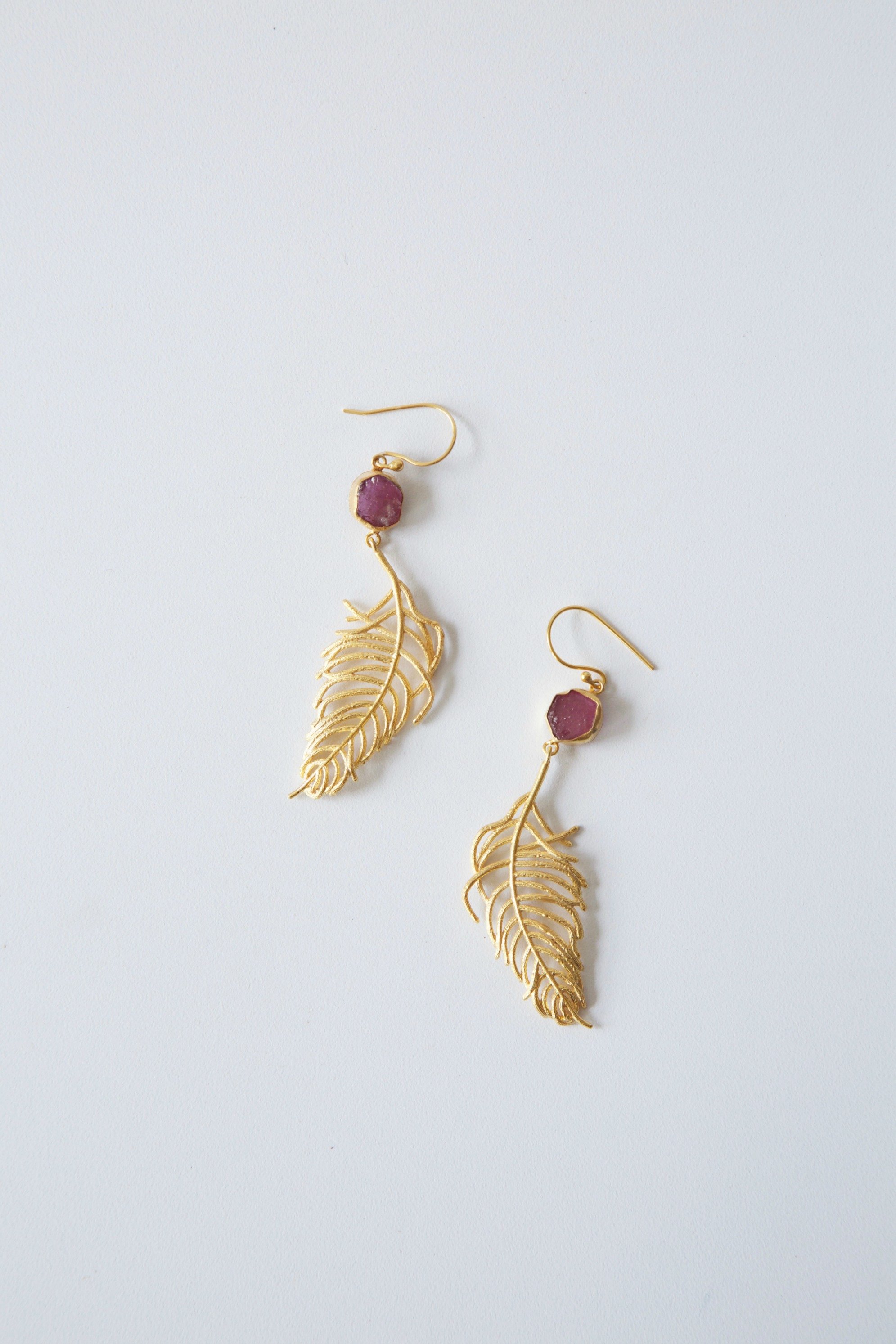 Elegant Cast Feather Earrings with 18K gold plating and clear quartz, showcasing a fluid feather design.