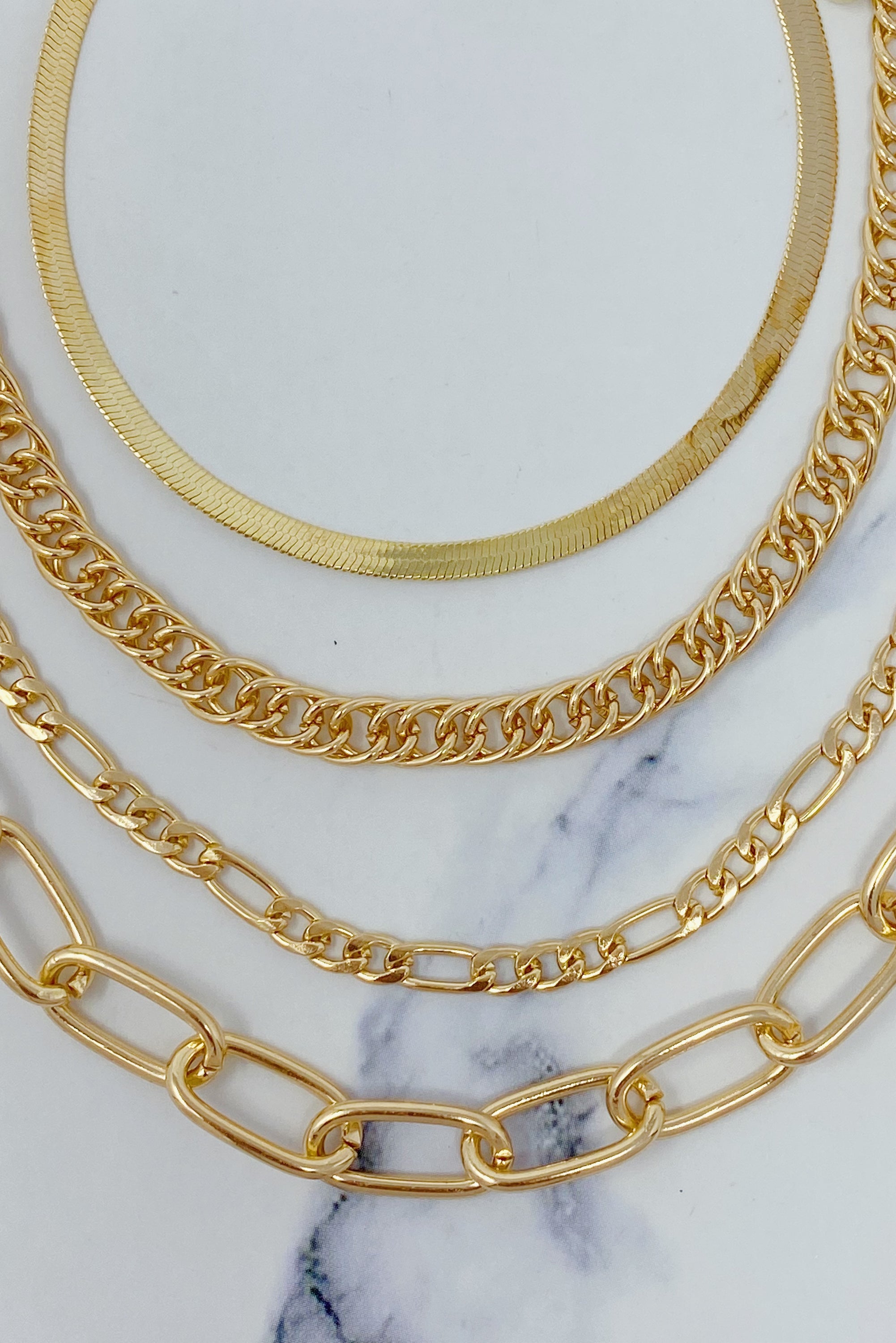 A stylish chain anklet set featuring four individual gold plated anklets, perfect for layering or wearing separately.