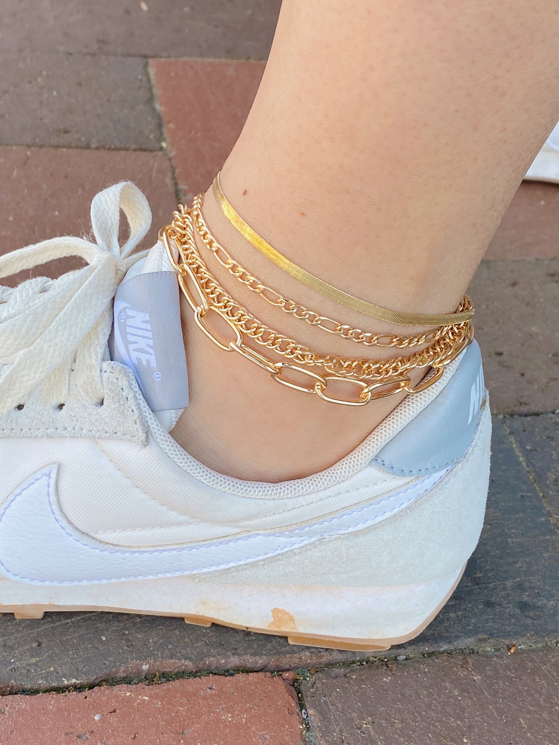 A stylish chain anklet set featuring four individual gold plated anklets, perfect for layering or wearing separately.