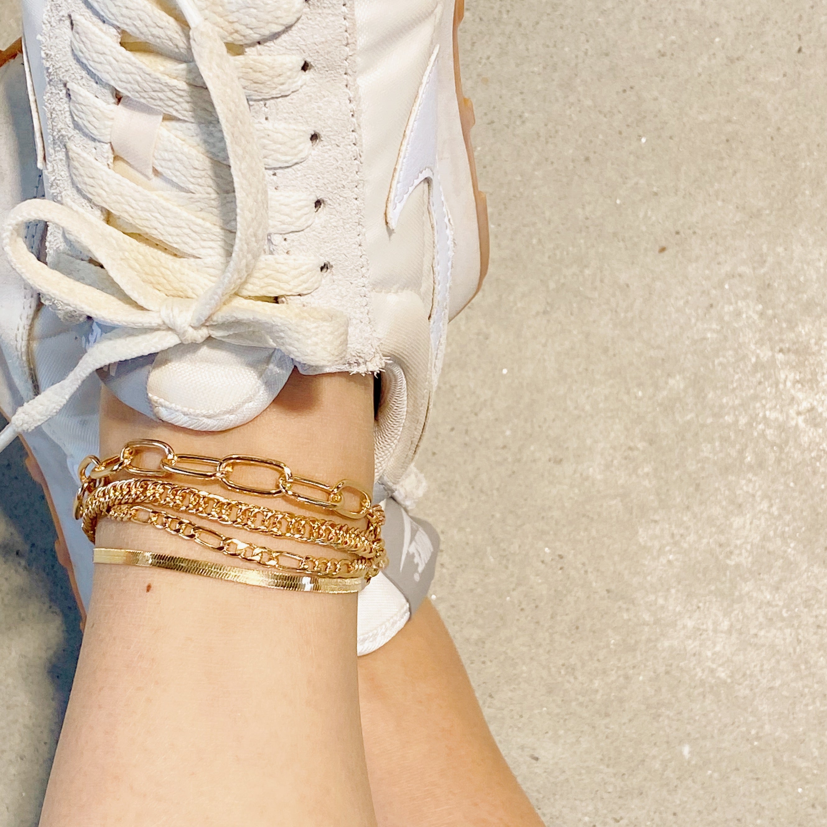 A stylish chain anklet set featuring four individual gold plated anklets, perfect for layering or wearing separately.