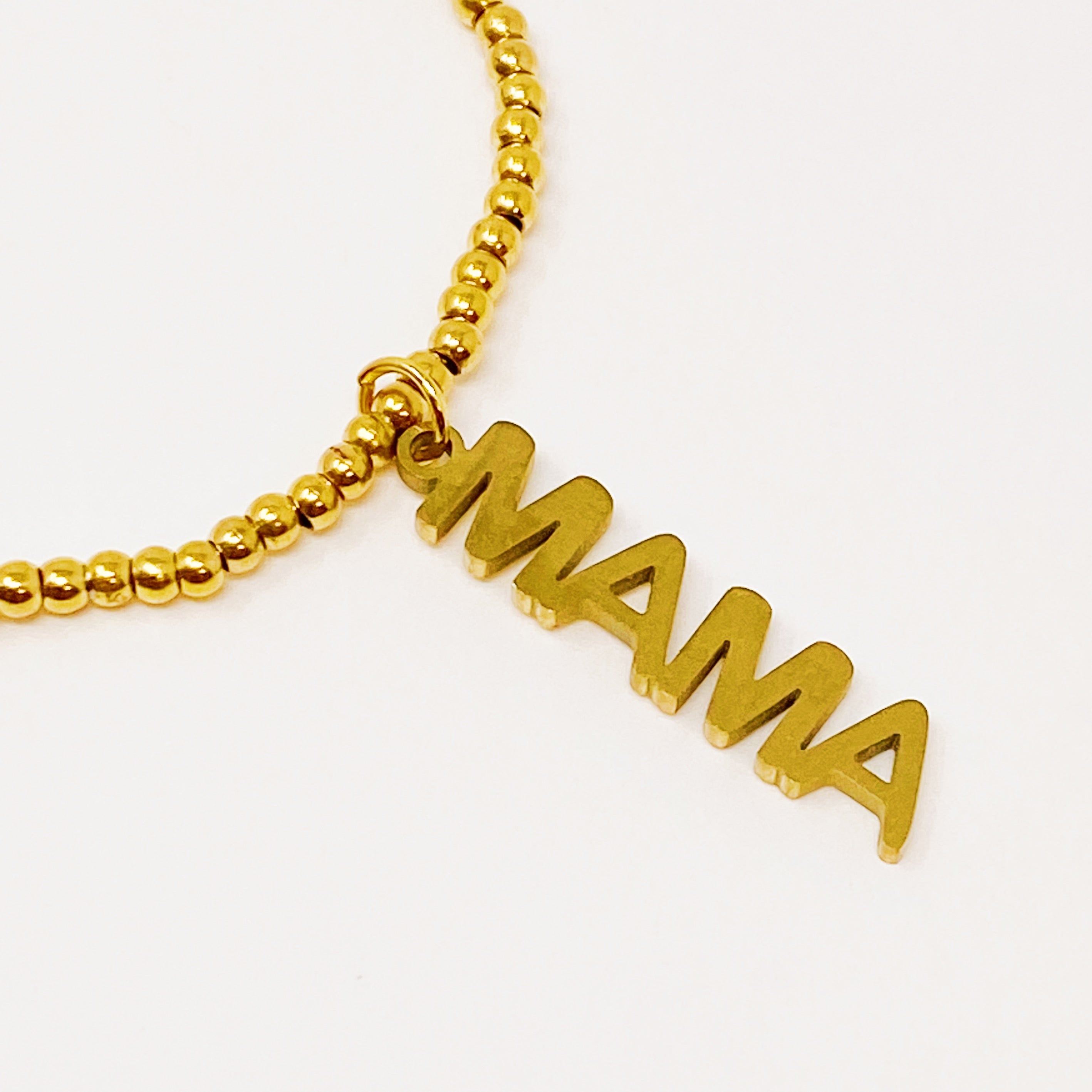 Charming Mama Stretch Bracelet featuring golden ball beads and a MAMA cutout charm, elegantly displayed on a soft background.