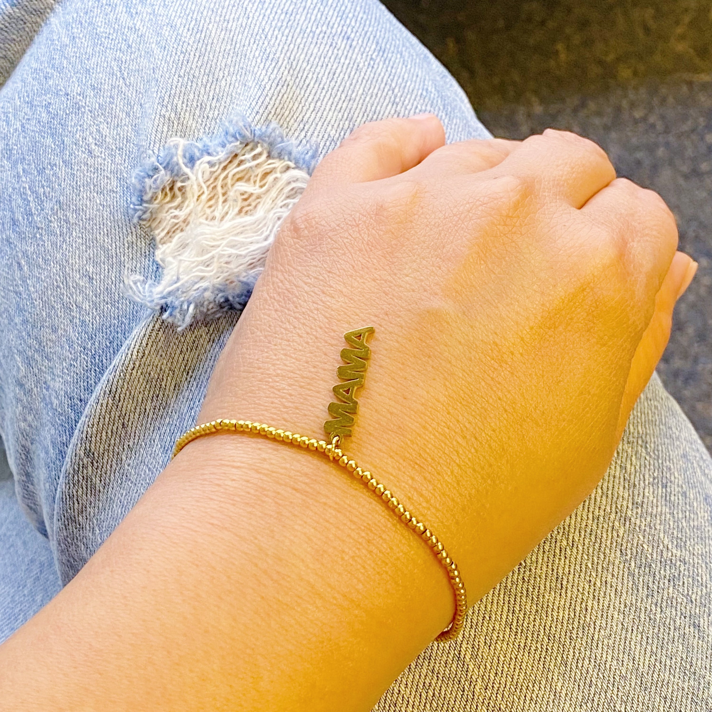 Charming Mama Stretch Bracelet featuring golden ball beads and a MAMA cutout charm, elegantly displayed on a soft background.