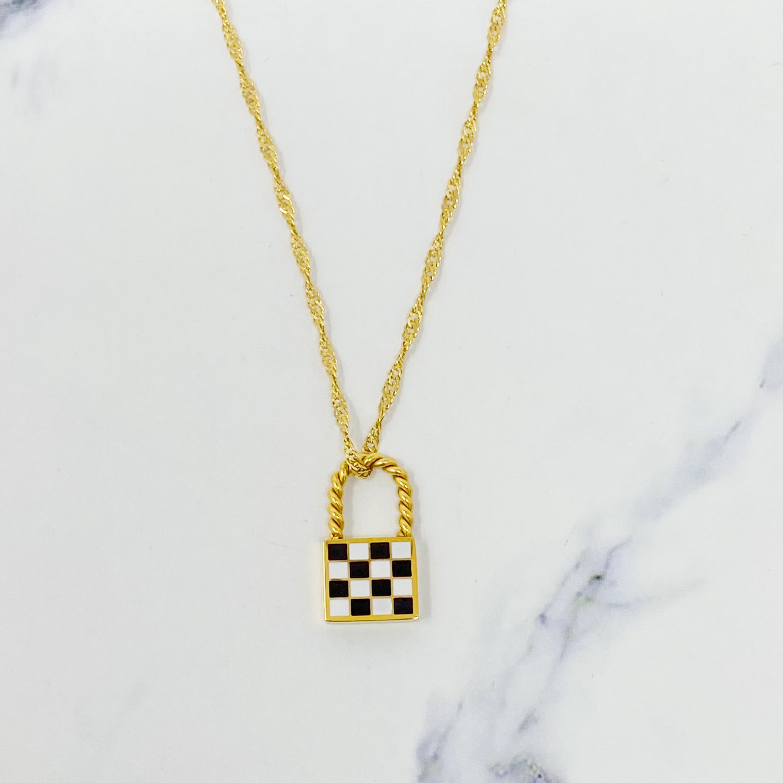 A stylish checkered locket necklace featuring a unique checkerboard pattern on the front and a polished back, hanging from a classy twist chain.