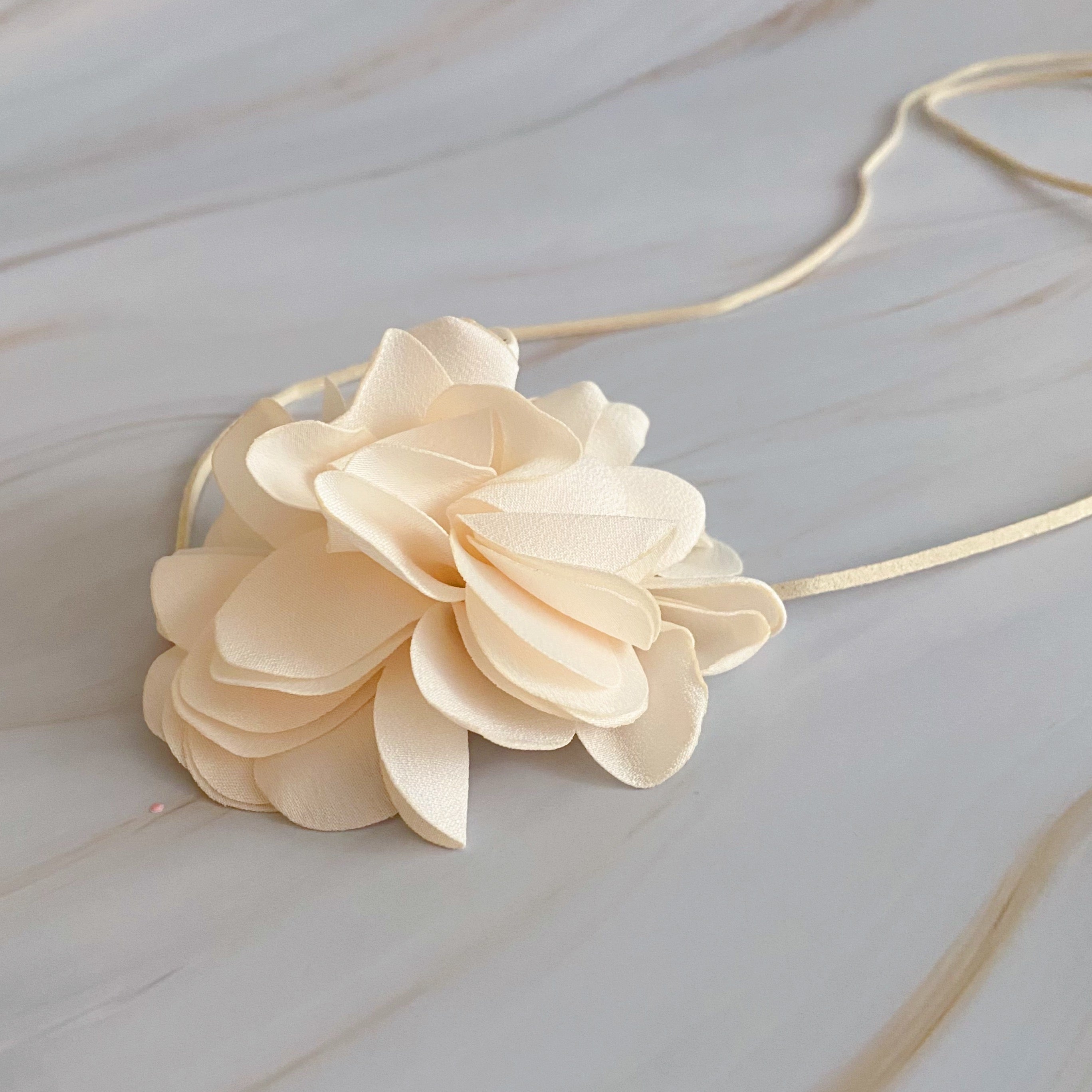 Chiffon Petals Rosette Tie necklace featuring a delicate fabric flower and a long slim strap, showcasing its versatility and lightweight design.