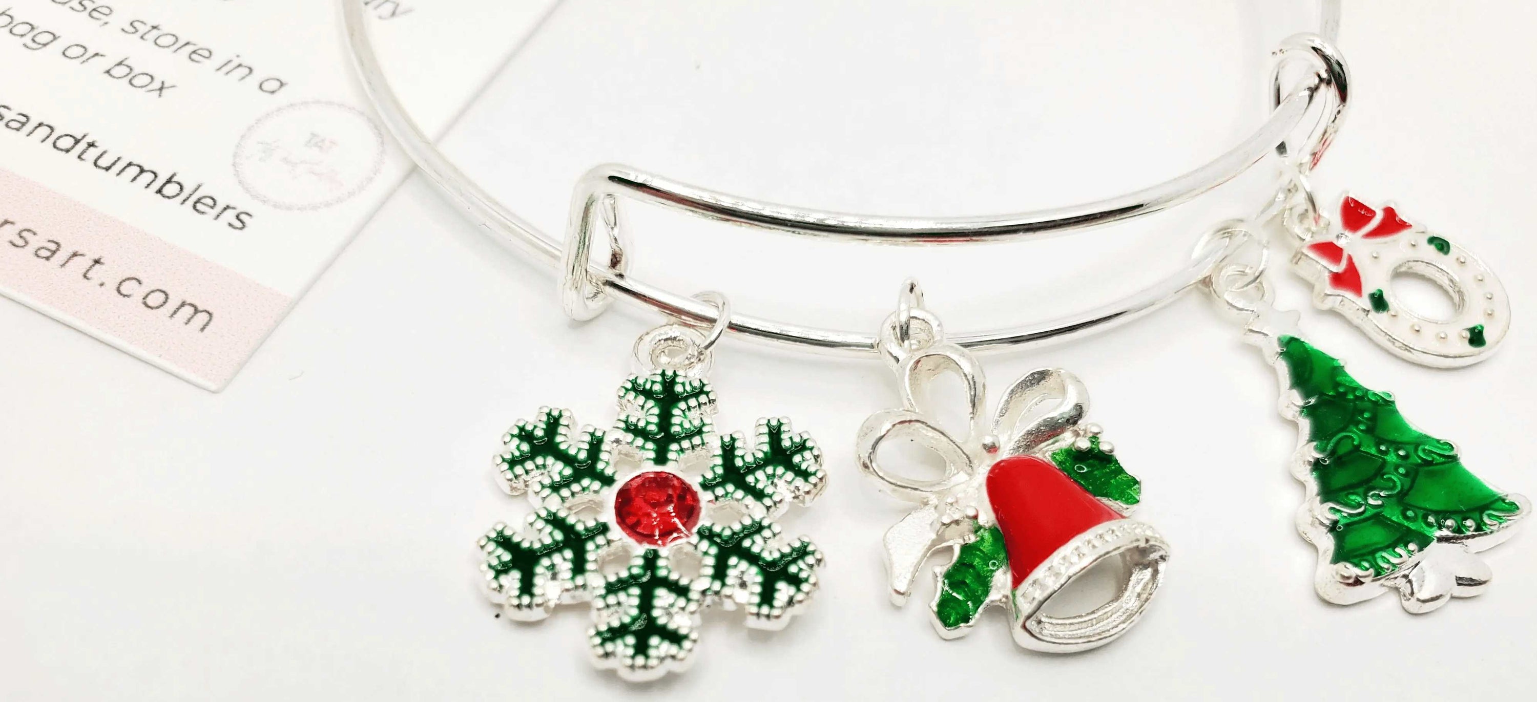 A beautiful silver Christmas charm bracelet featuring festive charms including a snowflake, bell, Christmas tree, and wreath.