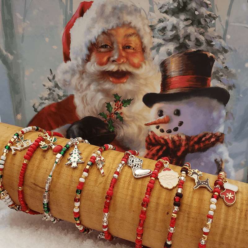 A collection of colorful Christmas Memory Wire Bracelets featuring glass beads and enameled charms, showcasing their unique design and festive spirit.