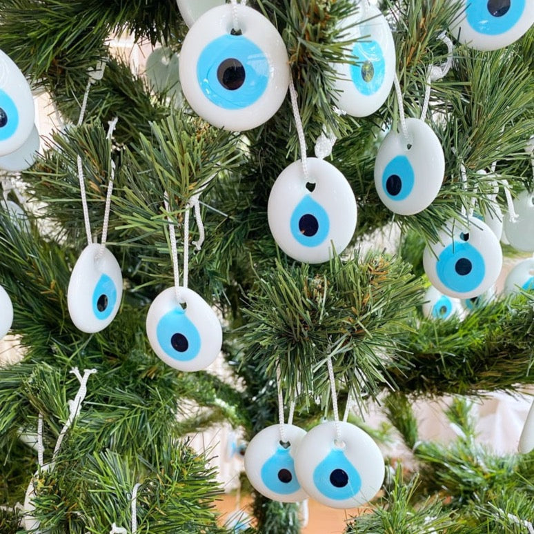 A collection of white evil eye bead Christmas tree ornaments made of glass, featuring intricate designs and hanging ropes for easy display.