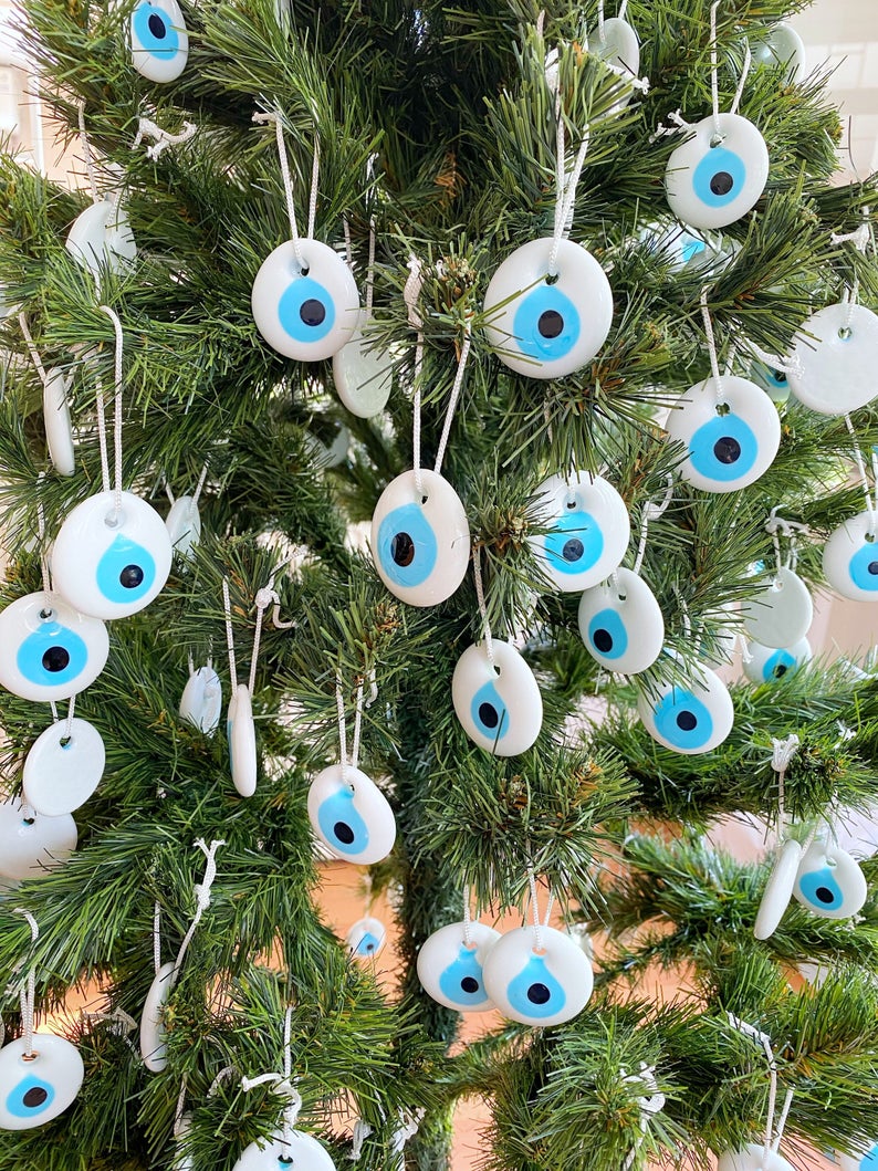 A collection of white evil eye bead Christmas tree ornaments made of glass, featuring intricate designs and hanging ropes for easy display.