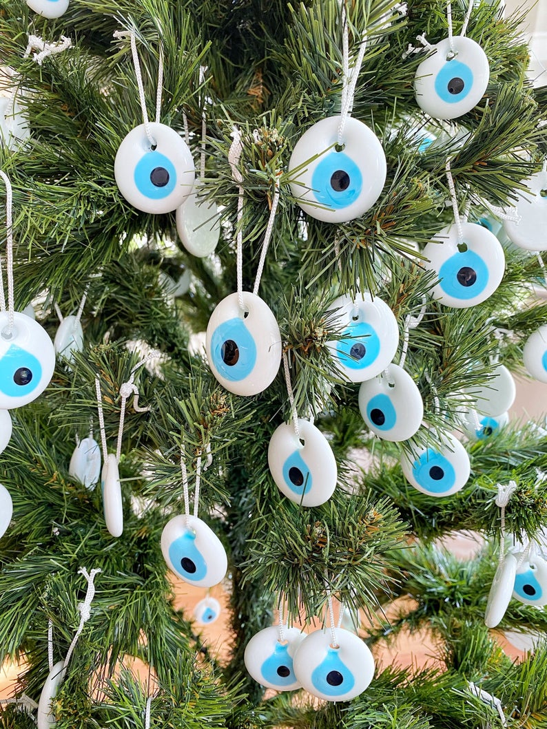 A collection of white evil eye bead Christmas tree ornaments made of glass, featuring intricate designs and hanging ropes for easy display.