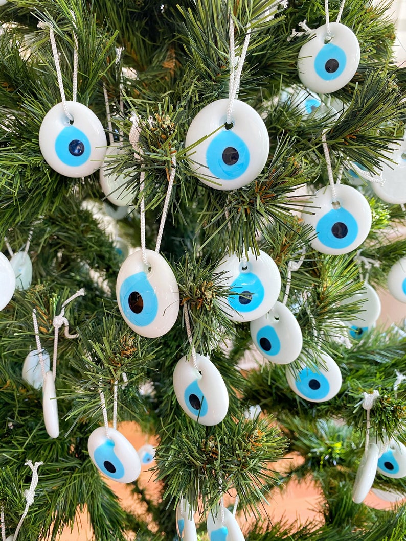 A collection of white evil eye bead Christmas tree ornaments made of glass, featuring intricate designs and hanging ropes for easy display.