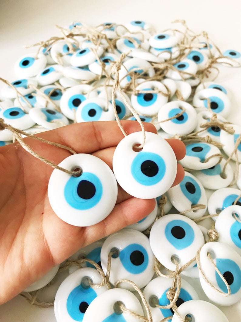 A collection of white evil eye bead Christmas tree ornaments made of glass, featuring intricate designs and hanging ropes for easy display.