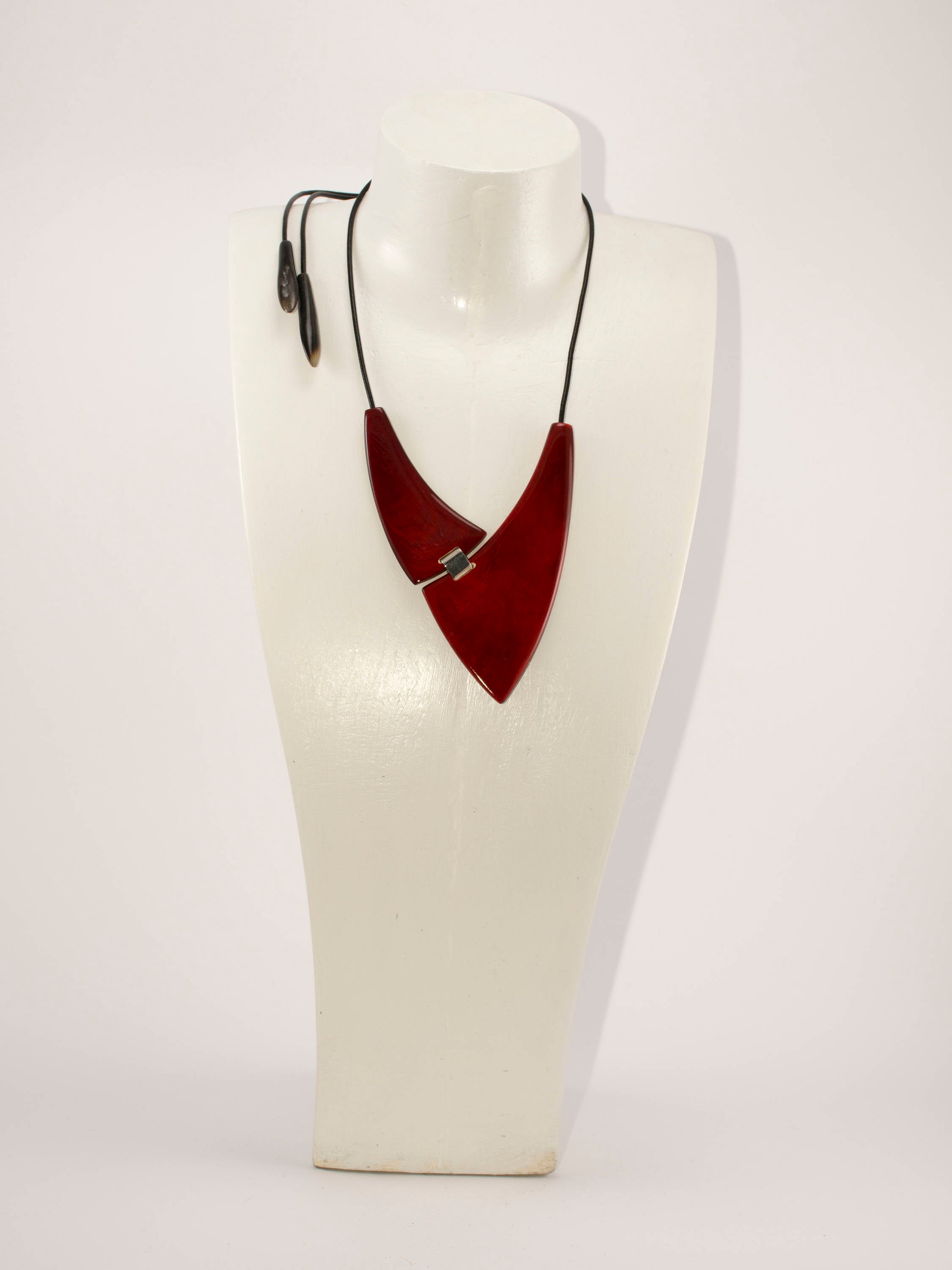 A chunky red necklace made from natural buffalo horns, featuring teardrop horn endings and an adjustable clasp, showcasing its unique design and craftsmanship.