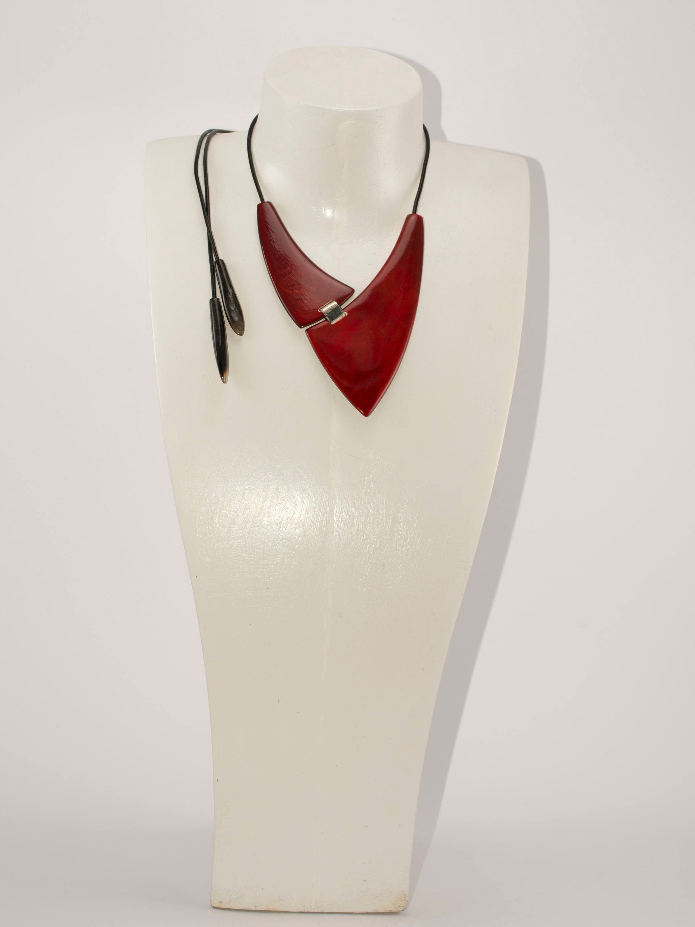 A chunky red necklace made from natural buffalo horns, featuring teardrop horn endings and an adjustable clasp, showcasing its unique design and craftsmanship.