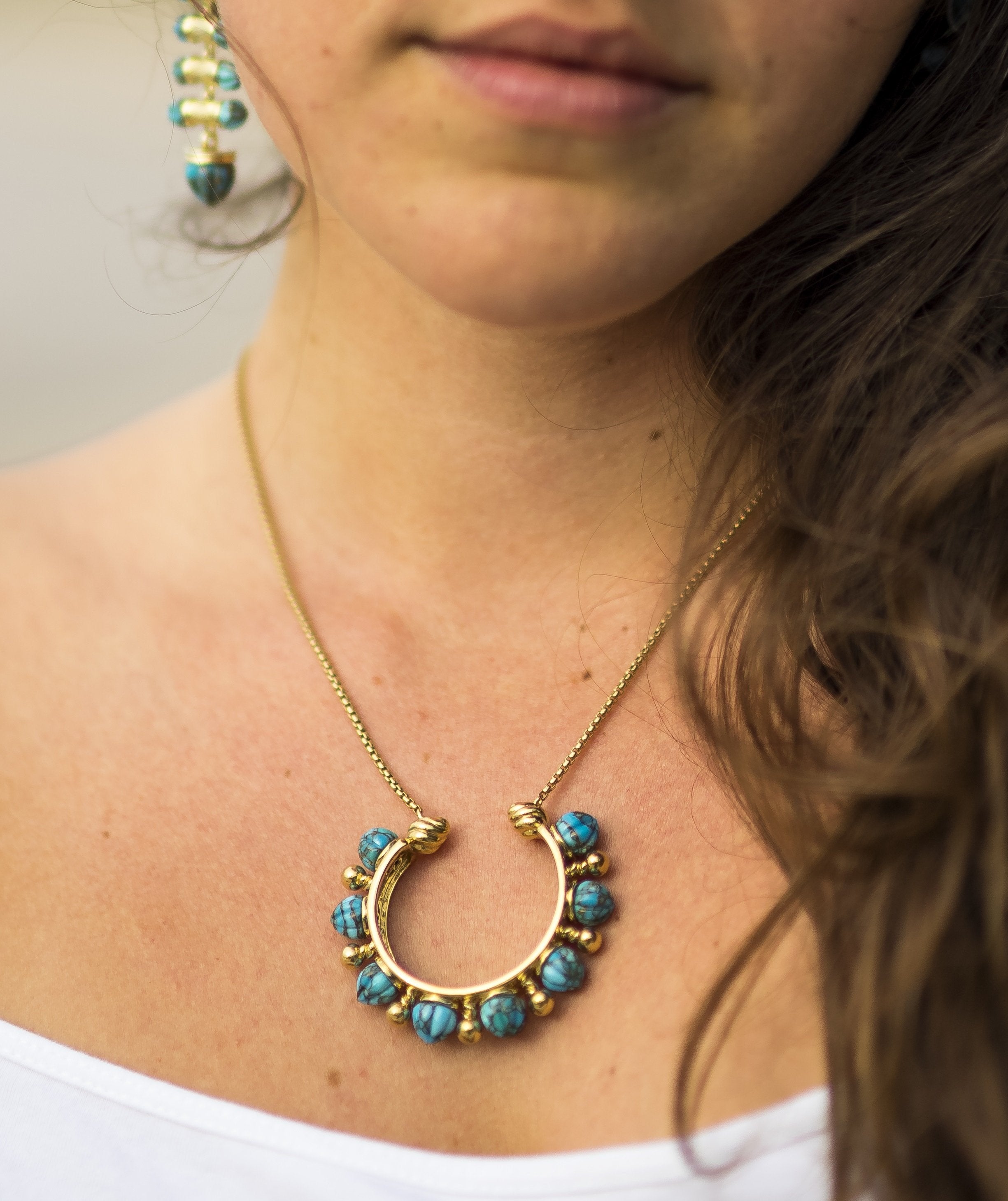 Circle of Fire Turquoise Necklace featuring carved turquoise stones and 14K yellow gold plating, elegantly displayed.