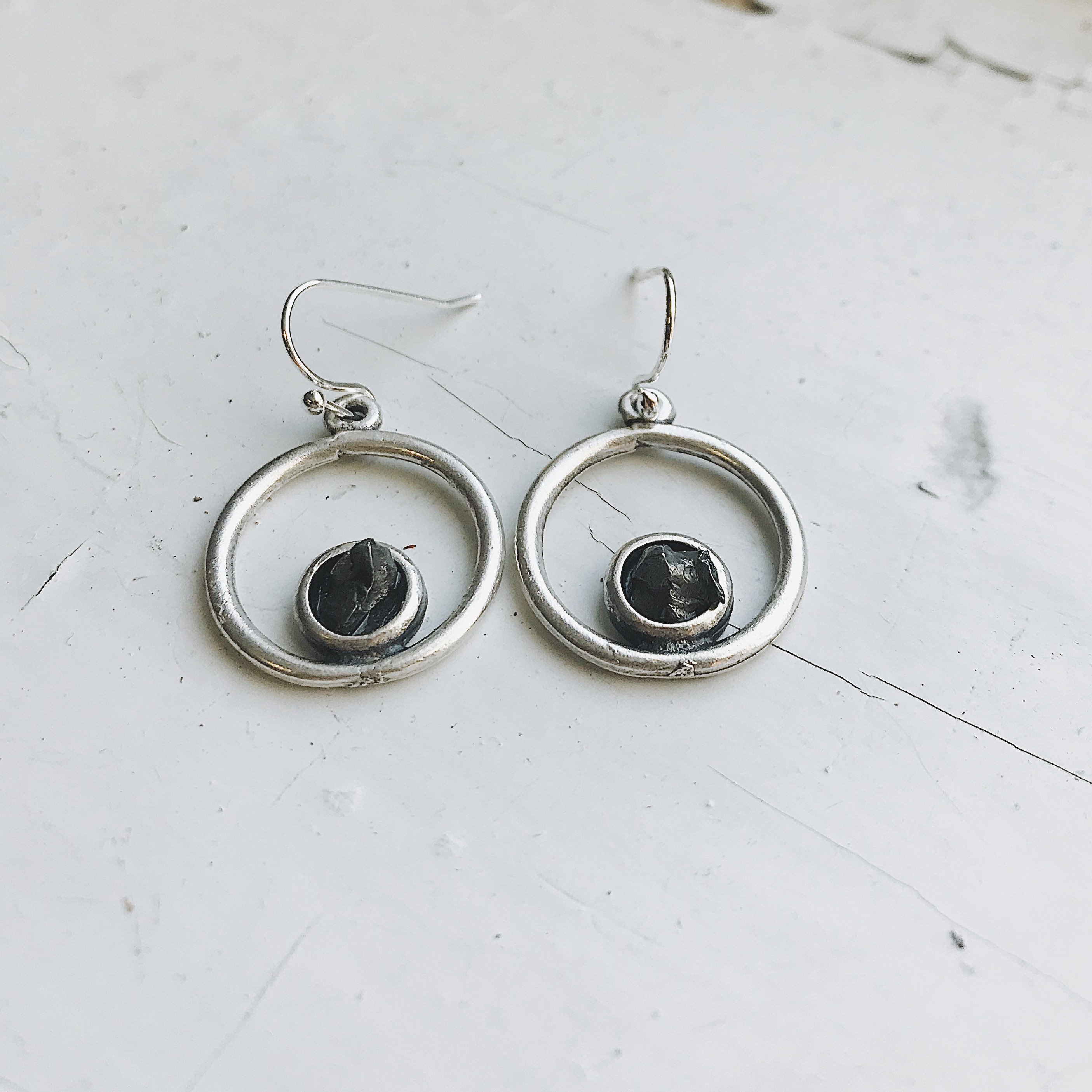 Circle silver earrings featuring raw Campo del Cielo meteorite in a bezel setting, showcasing a unique celestial design.