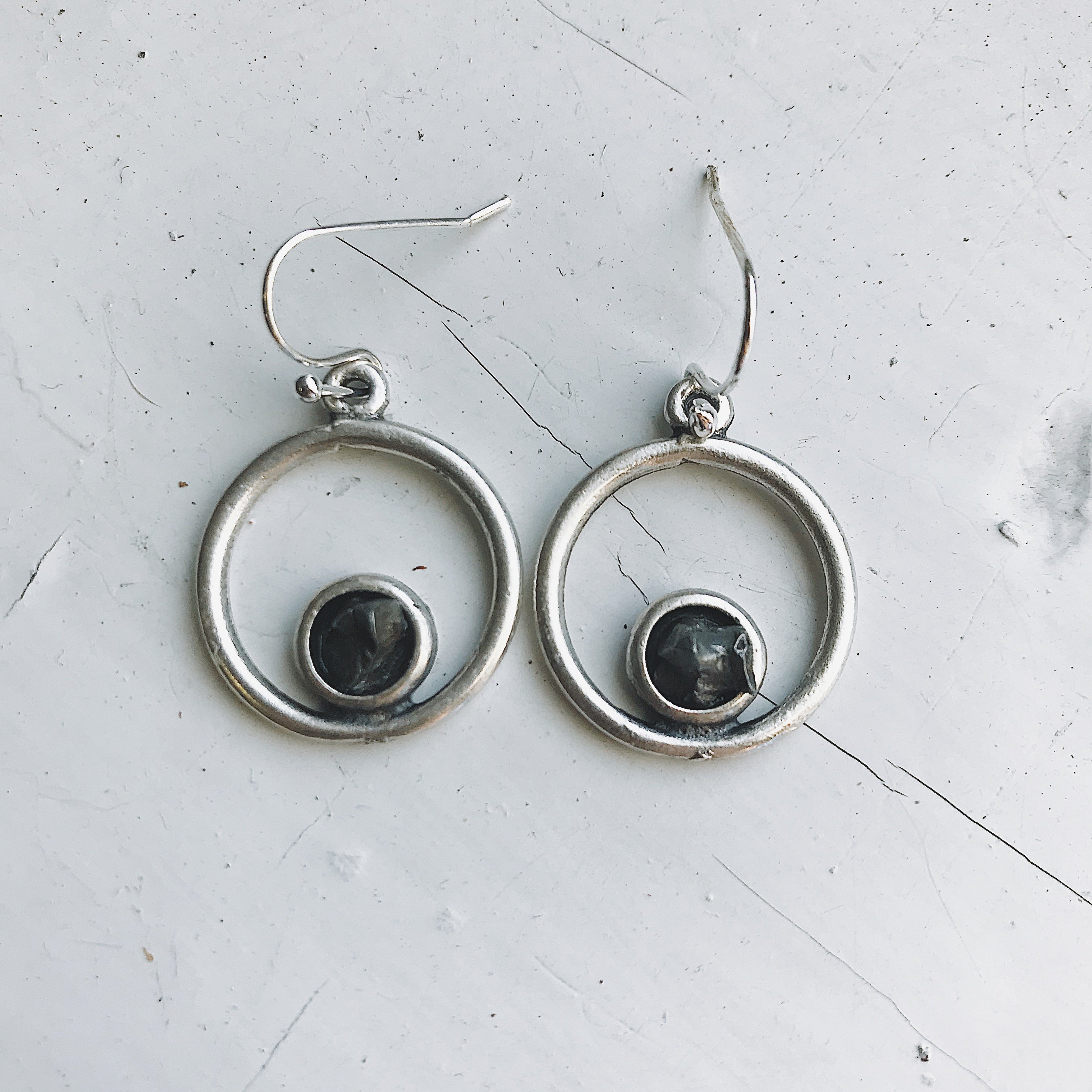 Circle silver earrings featuring raw Campo del Cielo meteorite in a bezel setting, showcasing a unique celestial design.