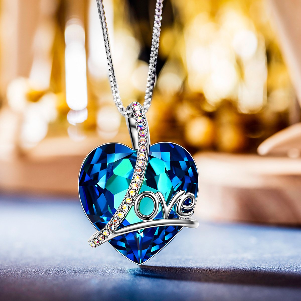 Classic Blue Love Heart Necklace featuring a Bermuda blue heart-shaped stone, 14K white gold plating, and an adjustable link chain.