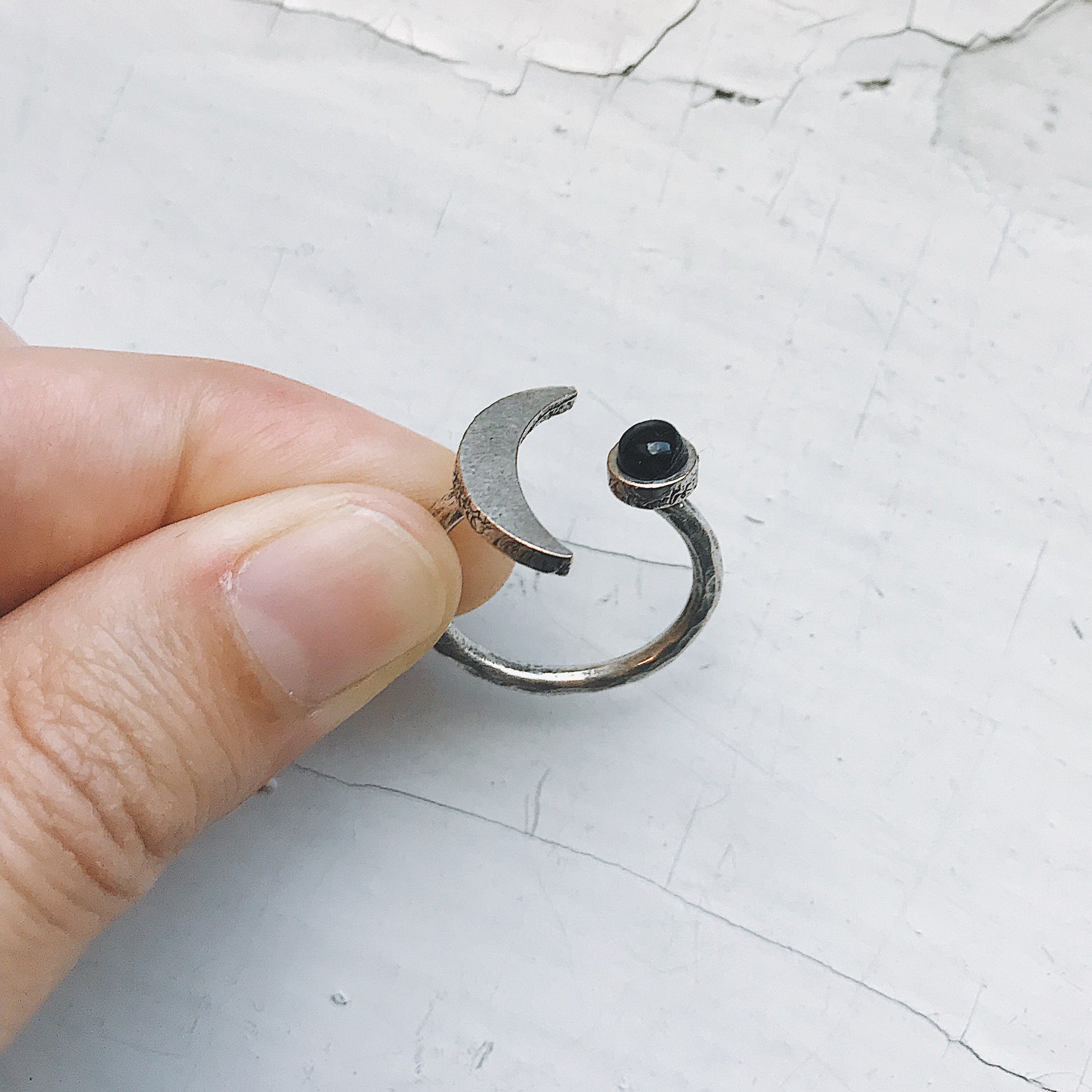 A beautifully handcrafted Crescent Moon Ring featuring a black onyx stone, available in silver or gold tone, showcasing its unique design.