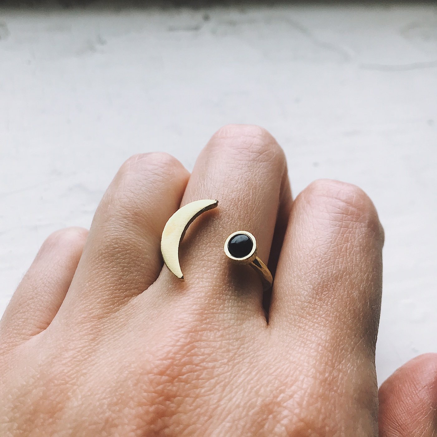 A beautifully handcrafted Crescent Moon Ring featuring a black onyx stone, available in silver or gold tone, showcasing its unique design.