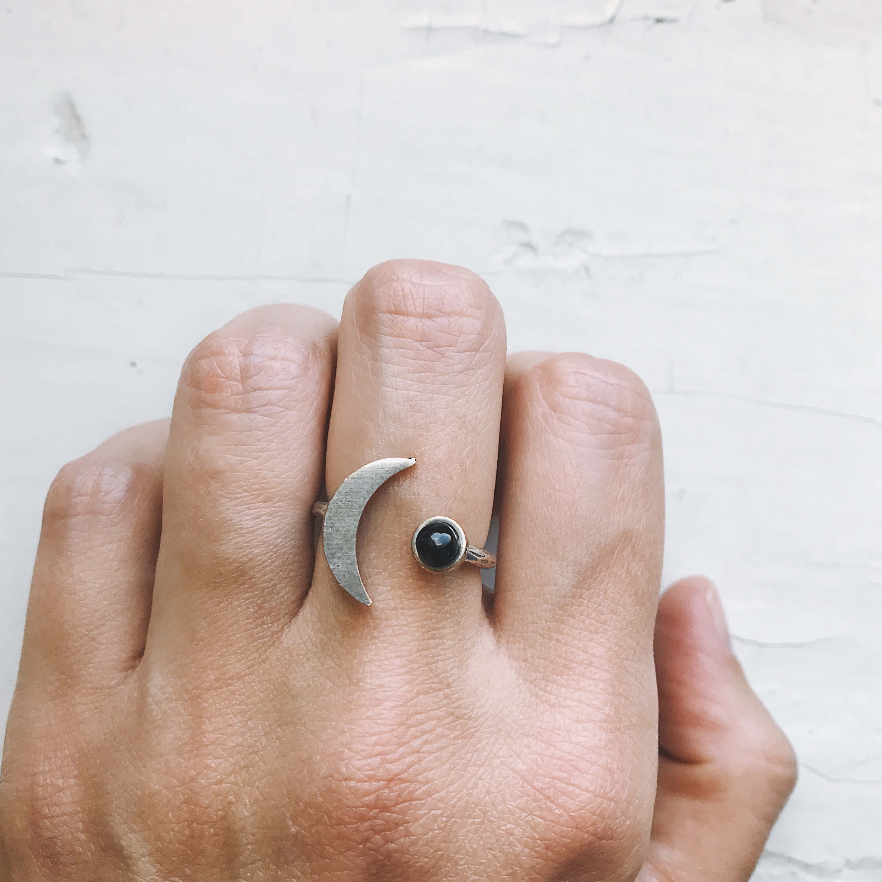 A beautifully handcrafted Crescent Moon Ring featuring a black onyx stone, available in silver or gold tone, showcasing its unique design.