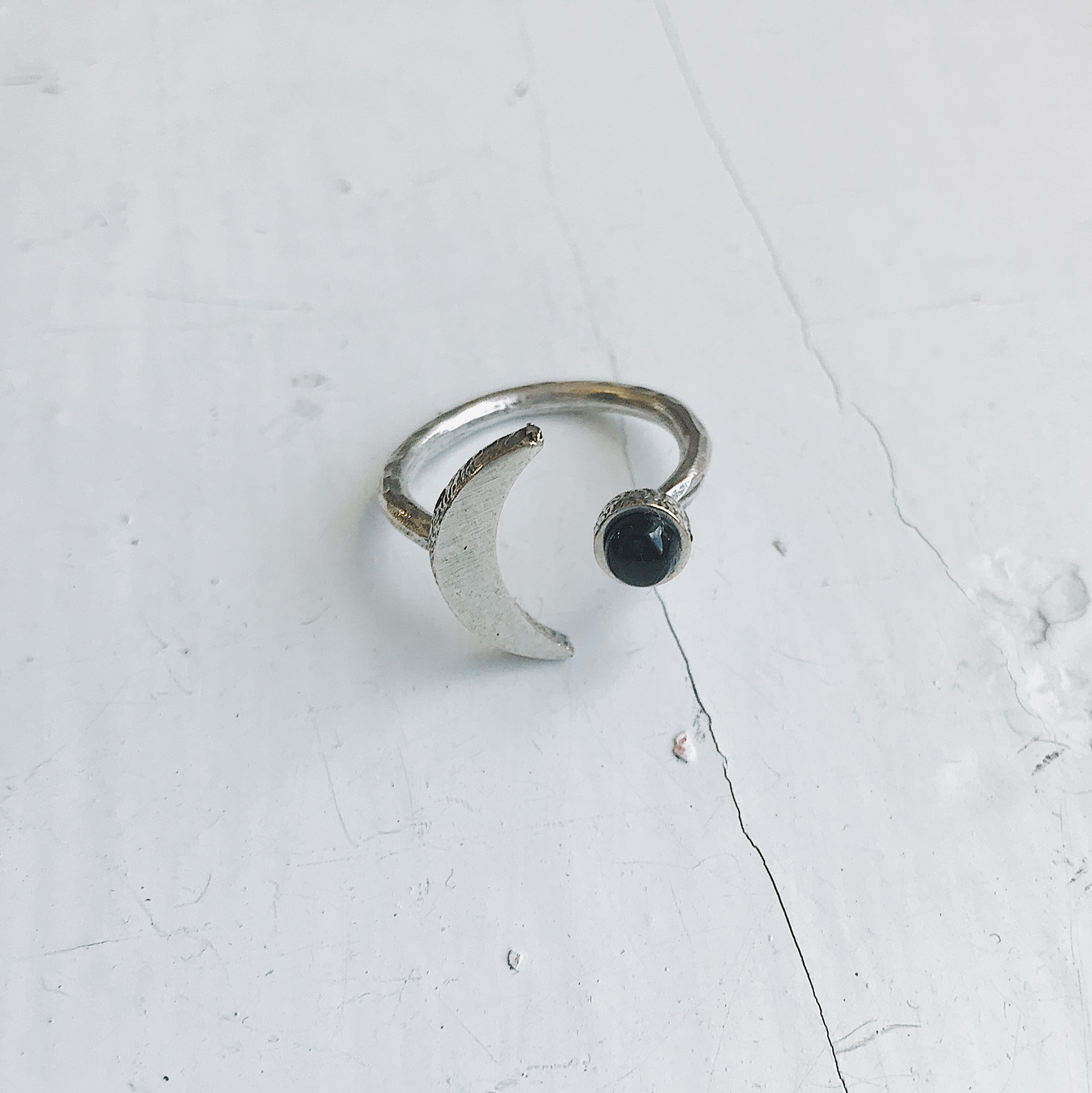 A beautifully handcrafted Crescent Moon Ring featuring a black onyx stone, available in silver or gold tone, showcasing its unique design.