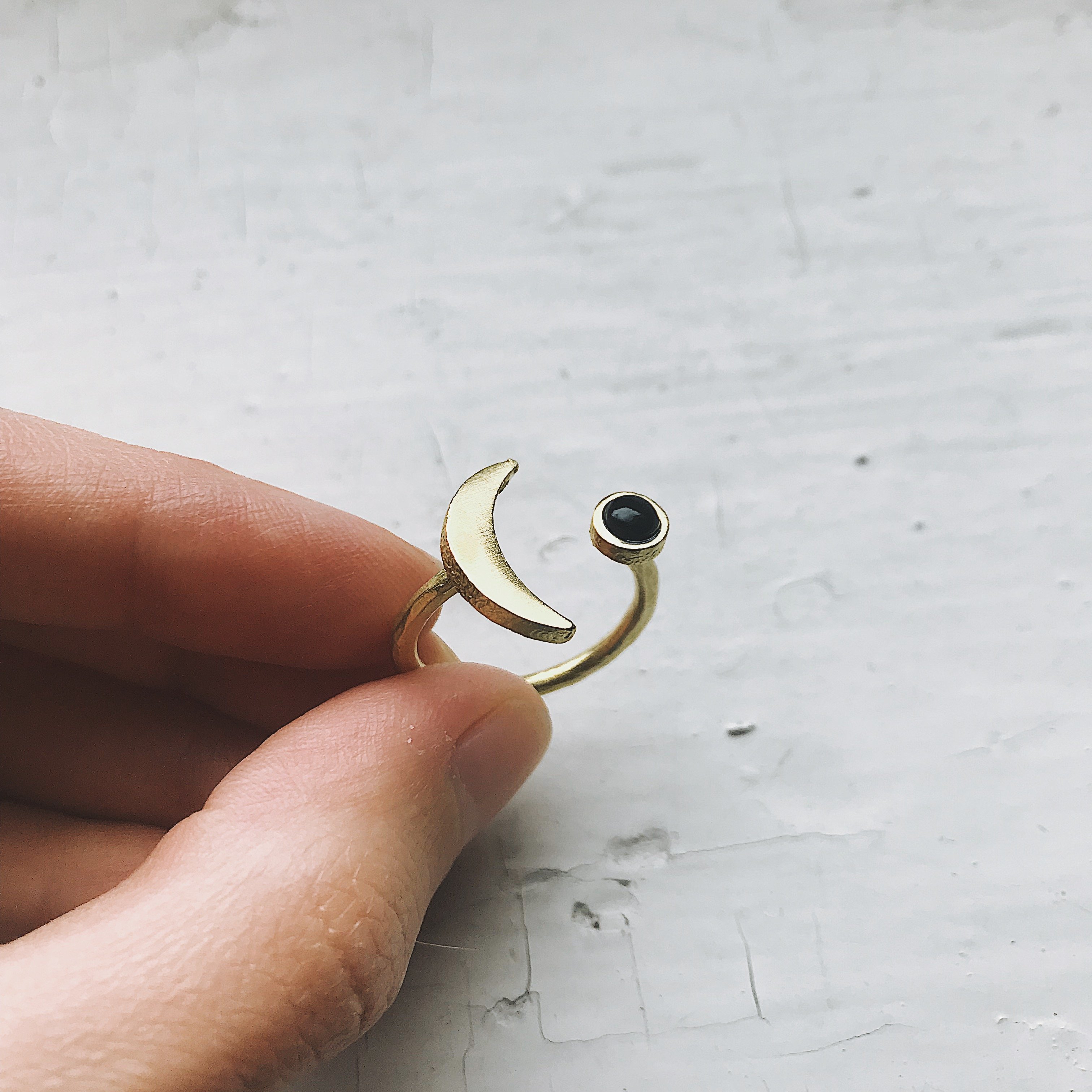 A beautifully handcrafted Crescent Moon Ring featuring a black onyx stone, available in silver or gold tone, showcasing its unique design.