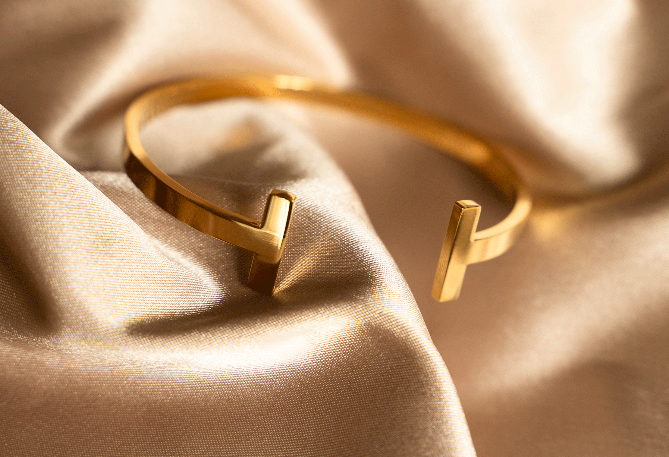 The CLEO Cuff is a stylish open bangle with a geometric 'T' shaped top, featuring 18K gold plating over stainless steel.