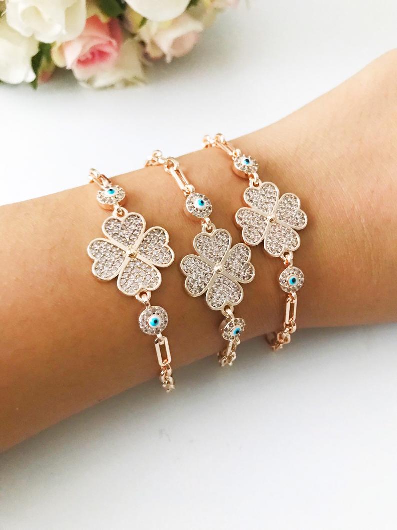 Clover Charm Bracelet featuring a blue evil eye bead and rose gold chain, showcasing its elegant design and unique charms.